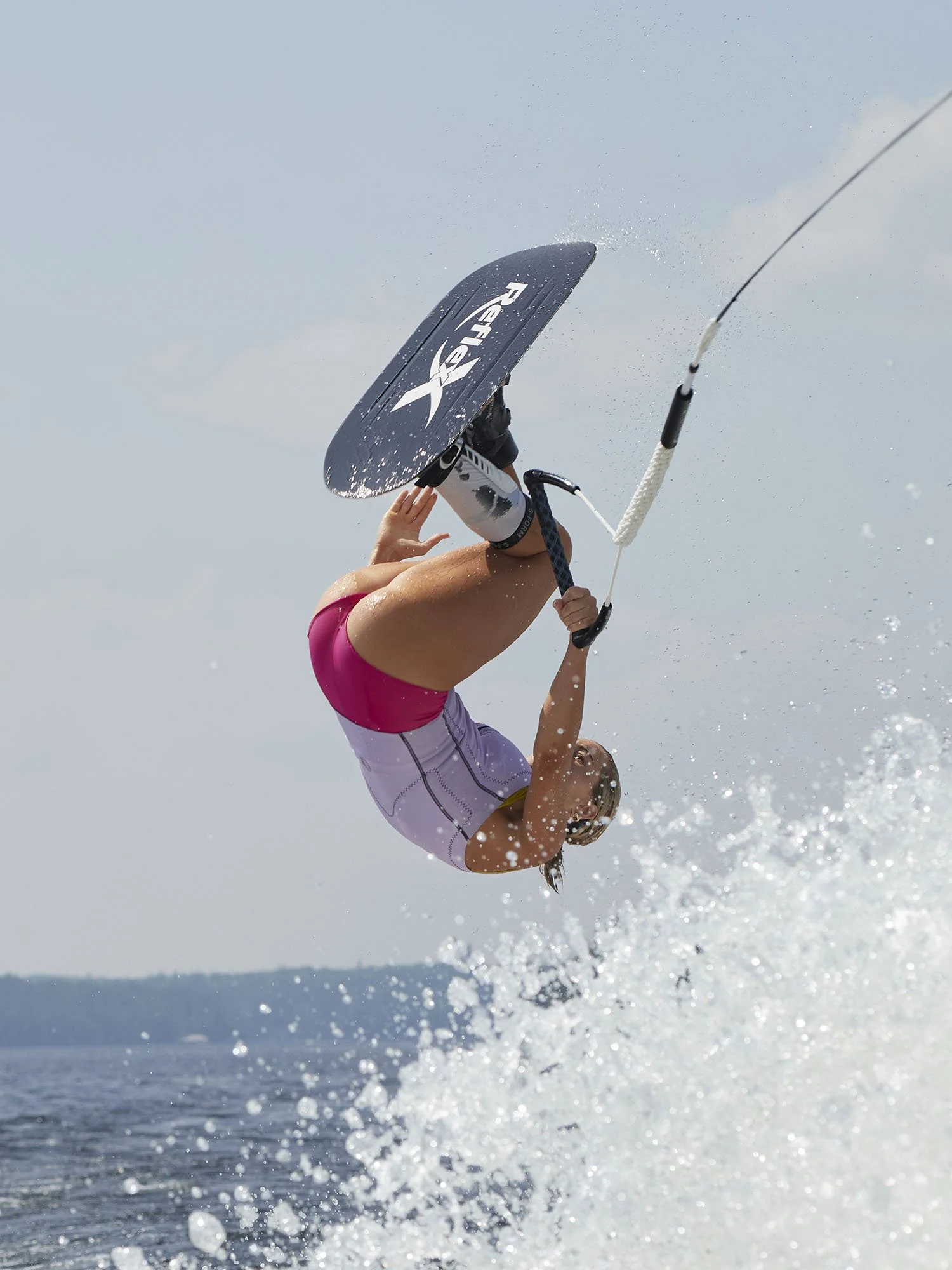 Water-skier backflipping over wake holding rope with handle