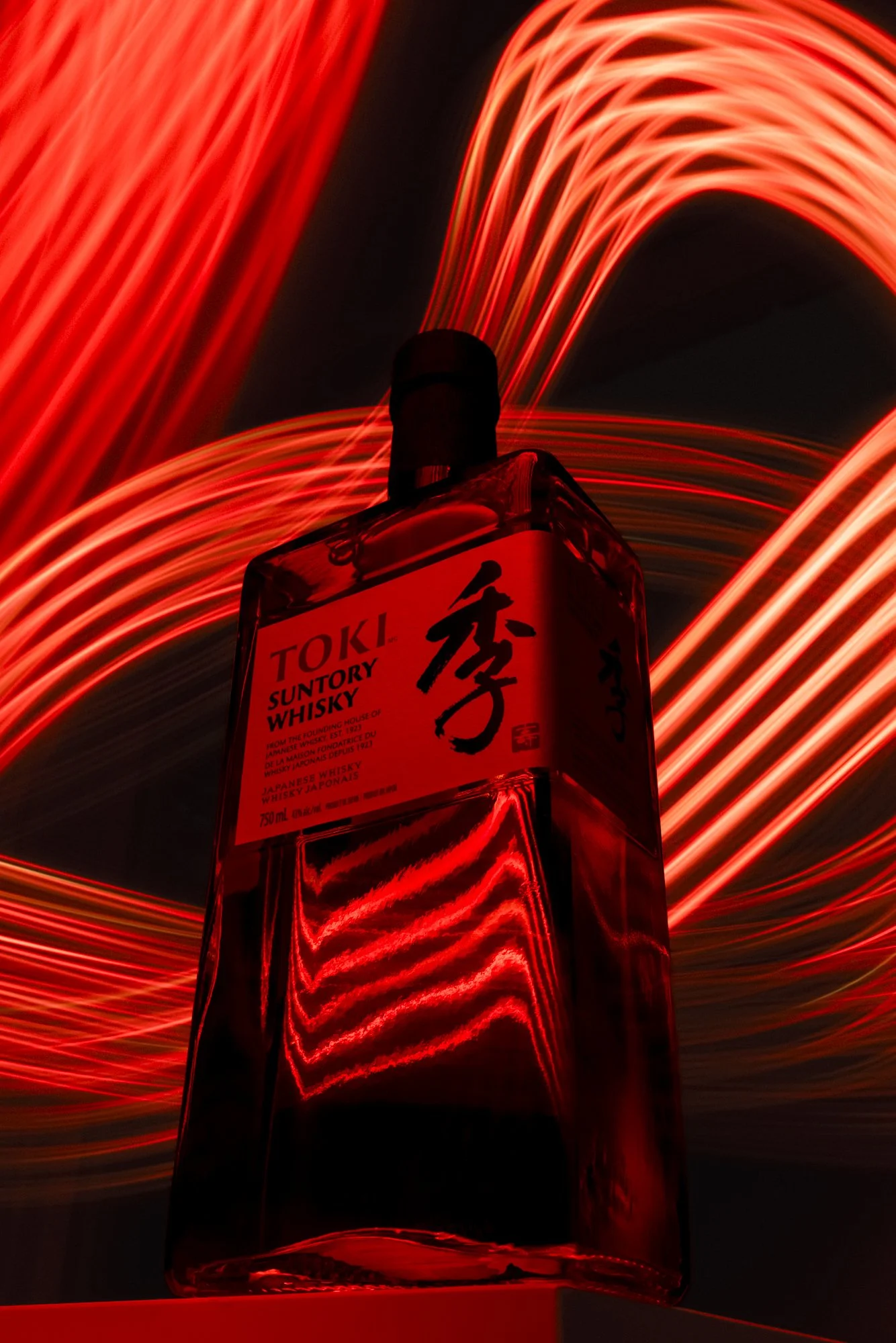 Toki whisky bottle with curved red light trails on a dark background.