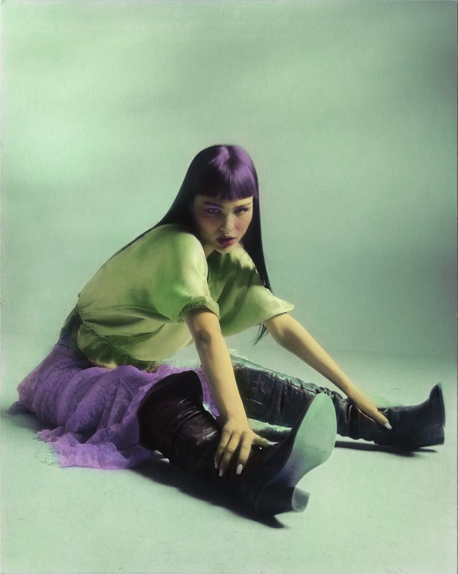 Woman sitting, legs extended, hands holding ankles, purple hair, wearing green blouse, purple skirt, brown boots, green textured background, hand coloured