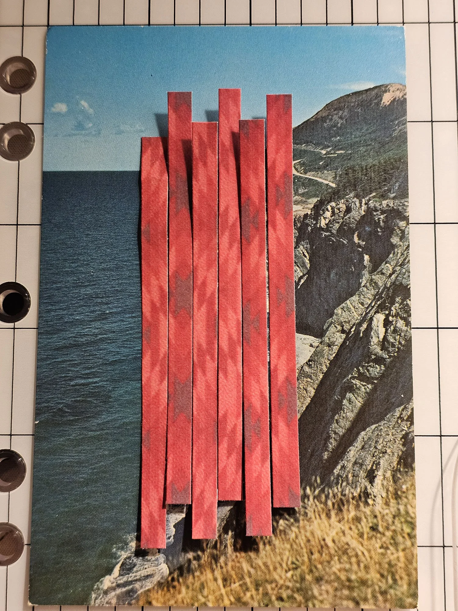 Collage of a coastal cliff and ocean with vertical red paper strips overlaid.