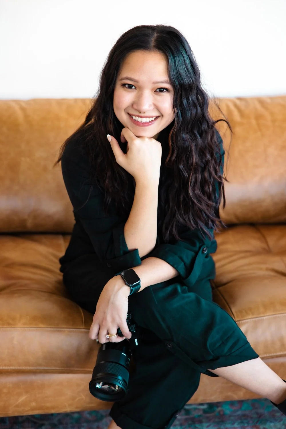 A lady sitting on the couch with a camera in her hands