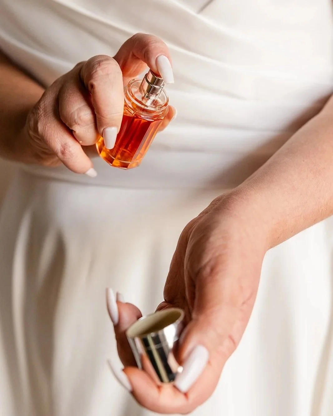 bride on wedding day spraying perfume on her wrist