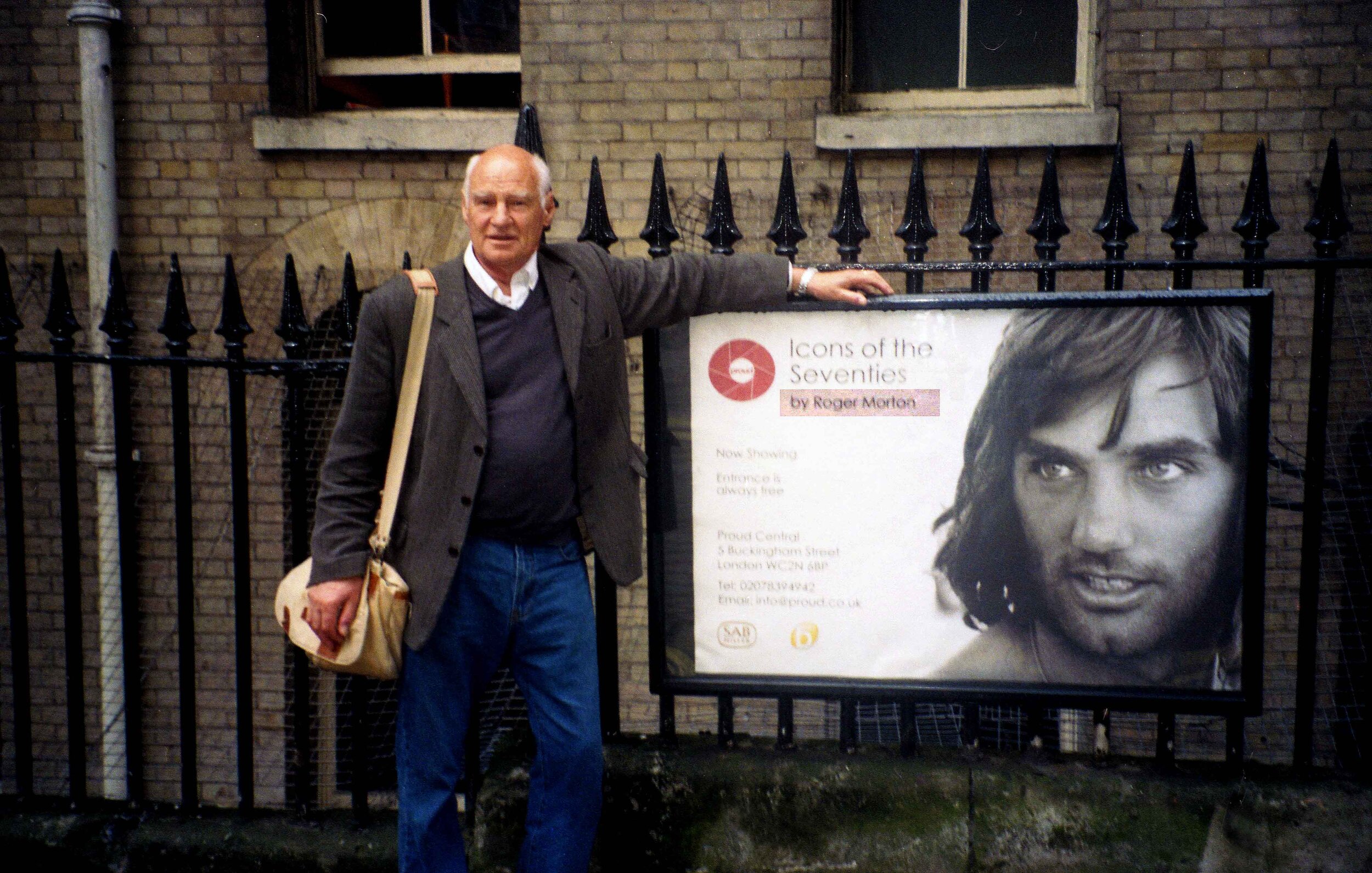 Roger Morton standing beside the poster for his solo exhibition.