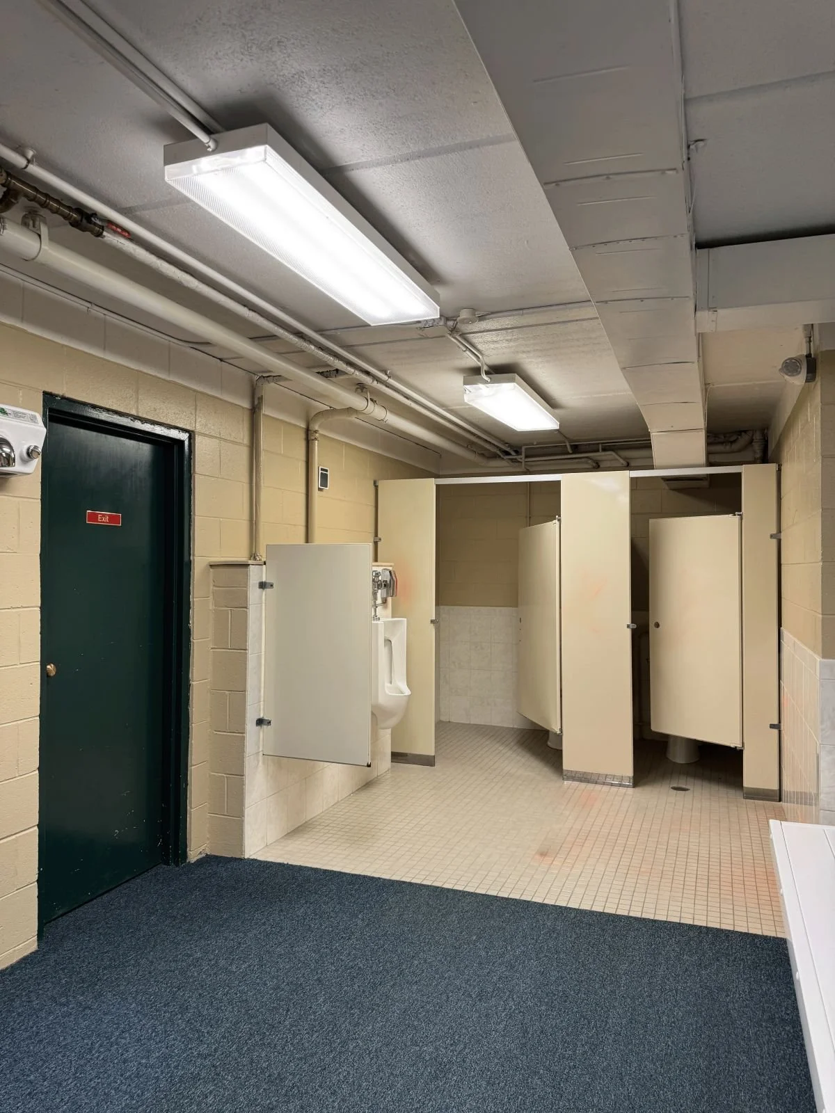 Existing men's toilet stalls prior to locker room renovation at Woburn Racquet Club