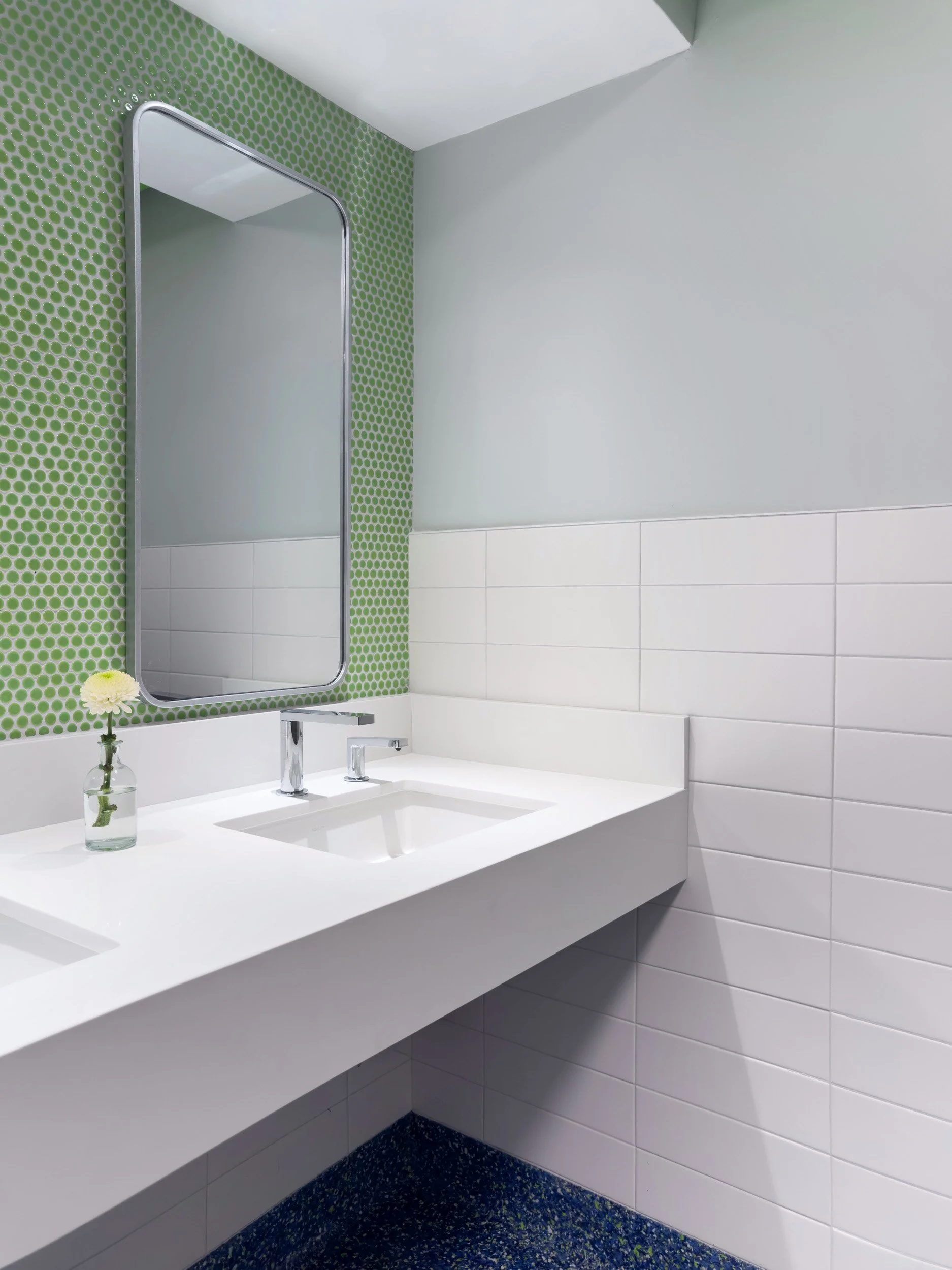 vanity detail at an undermount sink with chrome touchless faucet and soap dispenser with green penny tile backsplash and a white quartz countertop with apron front