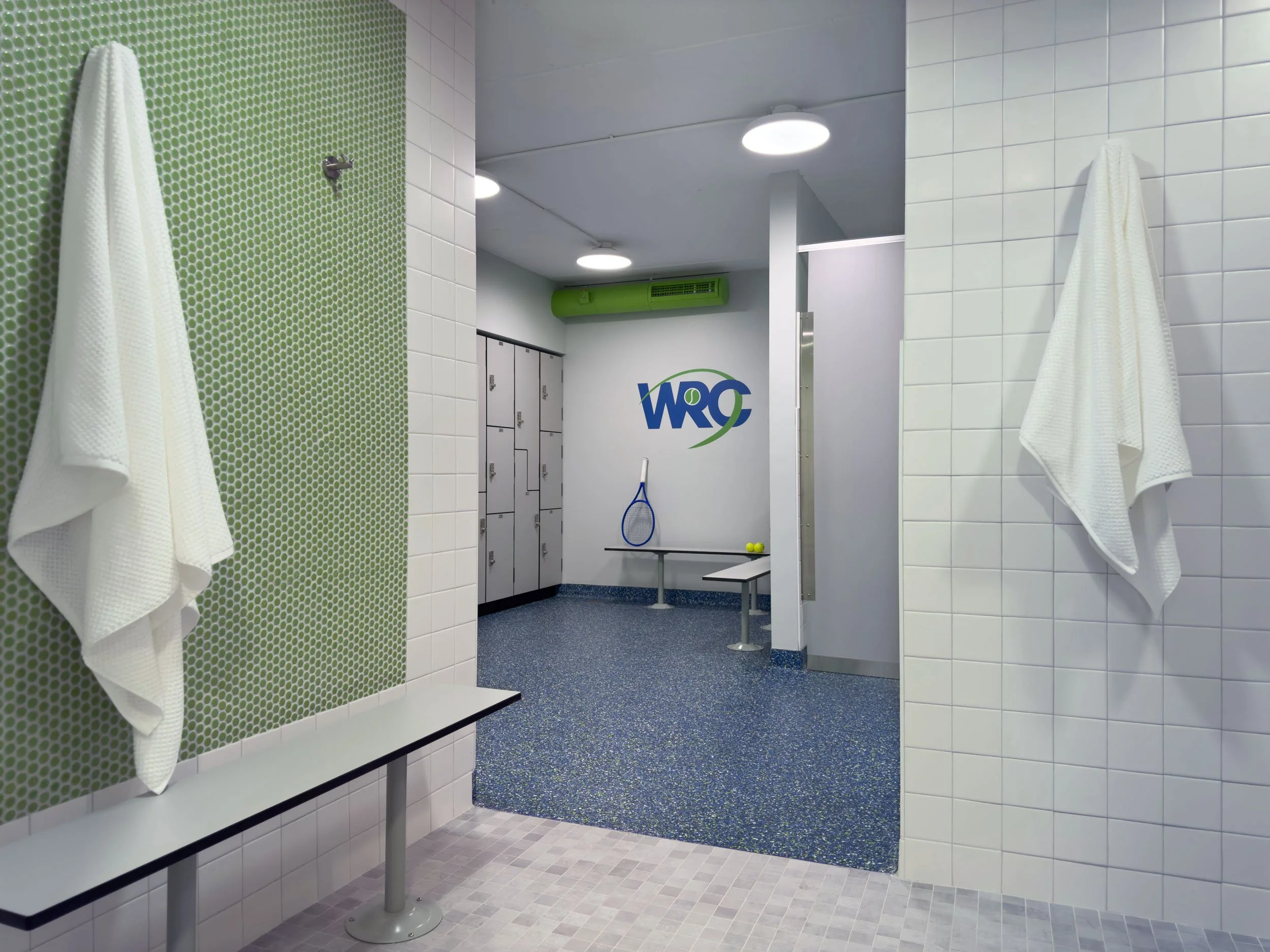 shower vestibule with green penny accent tile and white square subway tiled walls looking into main locker area
