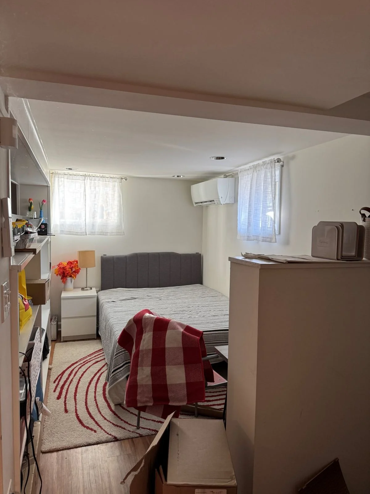 Basement guest bedroom with low ceiling and mini split air conditioner