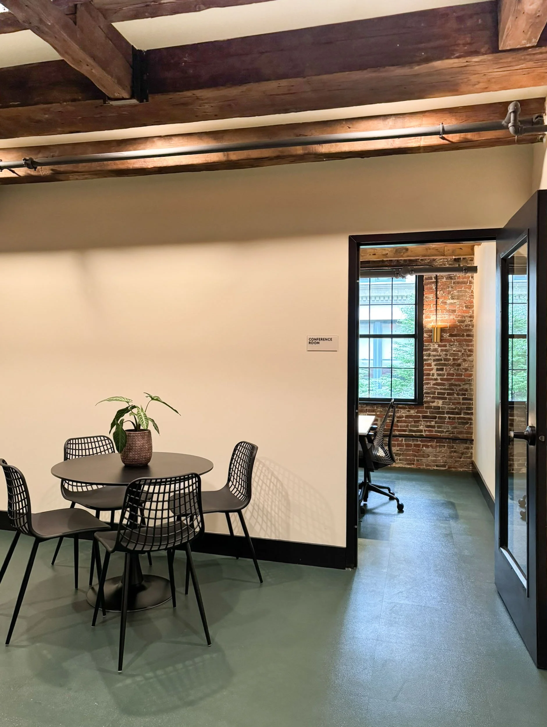 An employee break room with a round table and chairs adjacent to a hallway in a converted commercial space in downtown Boston.