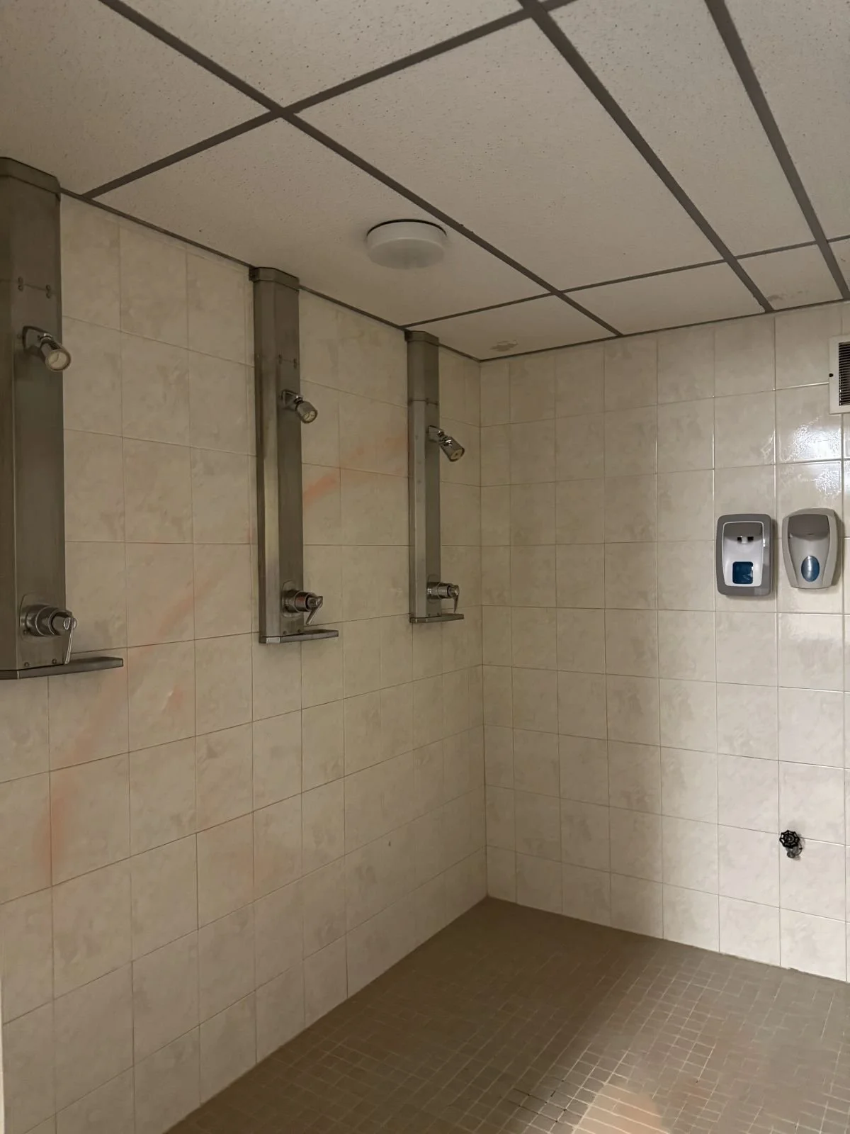 Existing men's showers prior to locker room renovation at Woburn Racquet Club