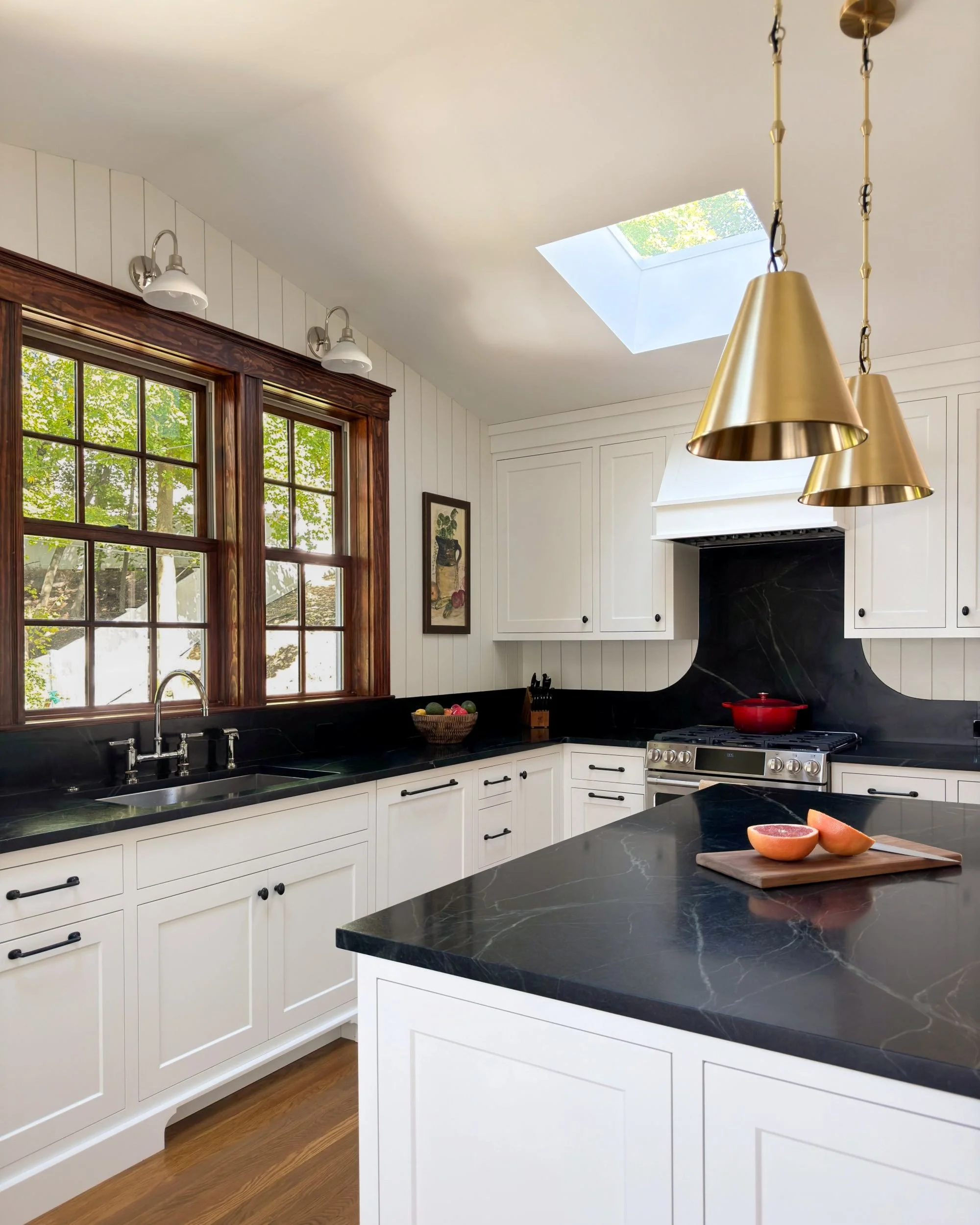 Renovated kitchen addition with soapstone island, brass pendant lighting, skylight, range with soapstone backsplash, and wood-framed windows, Medford MA