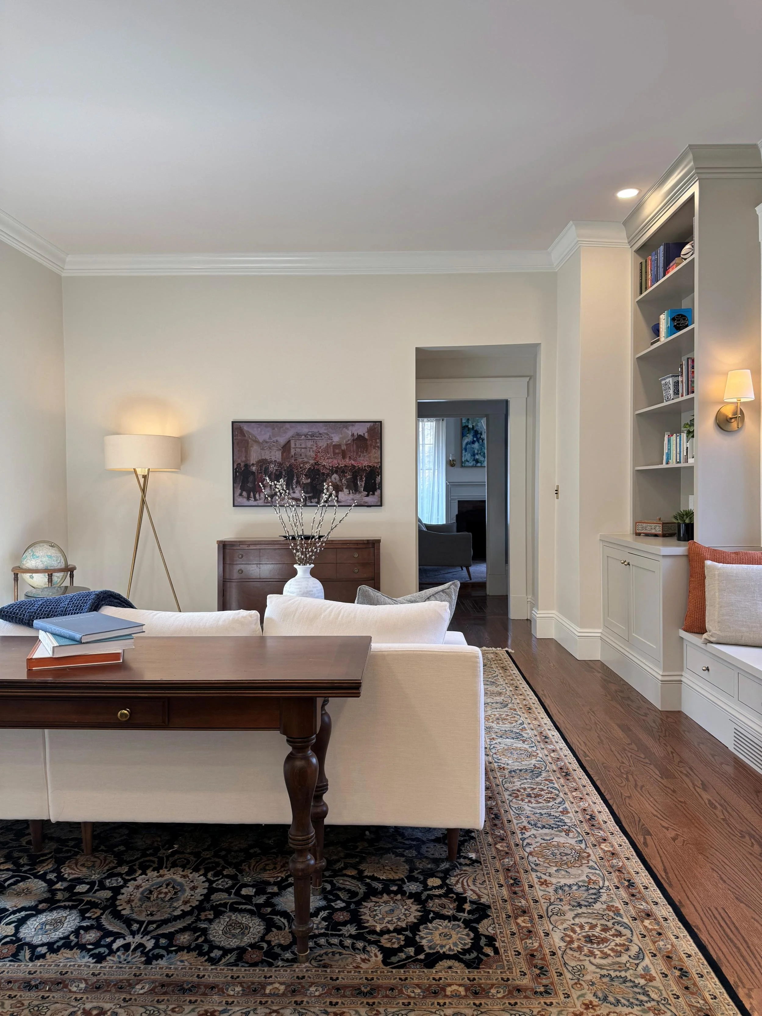 Relocated and renovated den of an 1846 Victorian home in Newton MA showing open layout with built-in bookshelves, hardwood floors and view through to formal living room