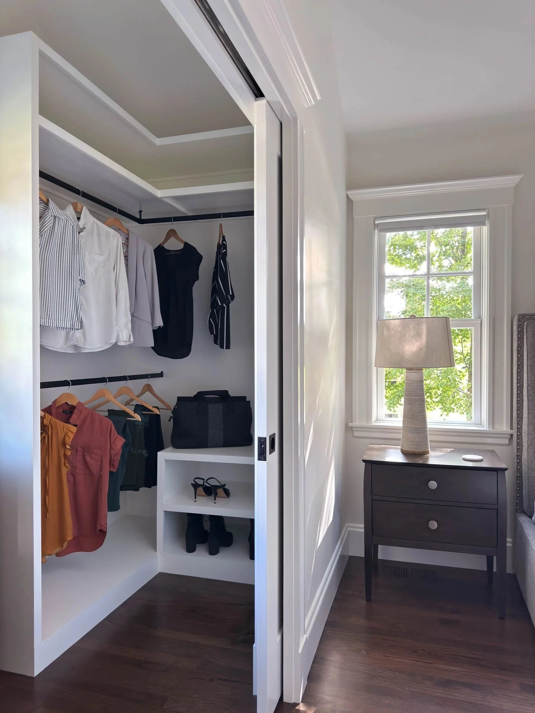 Her side of a his and hers walk-in closet in a Dutch Colonial primary suite addition in Greater Boston showing custom built-in shelving and hanging rods designed by Tact and Grit Design Co.