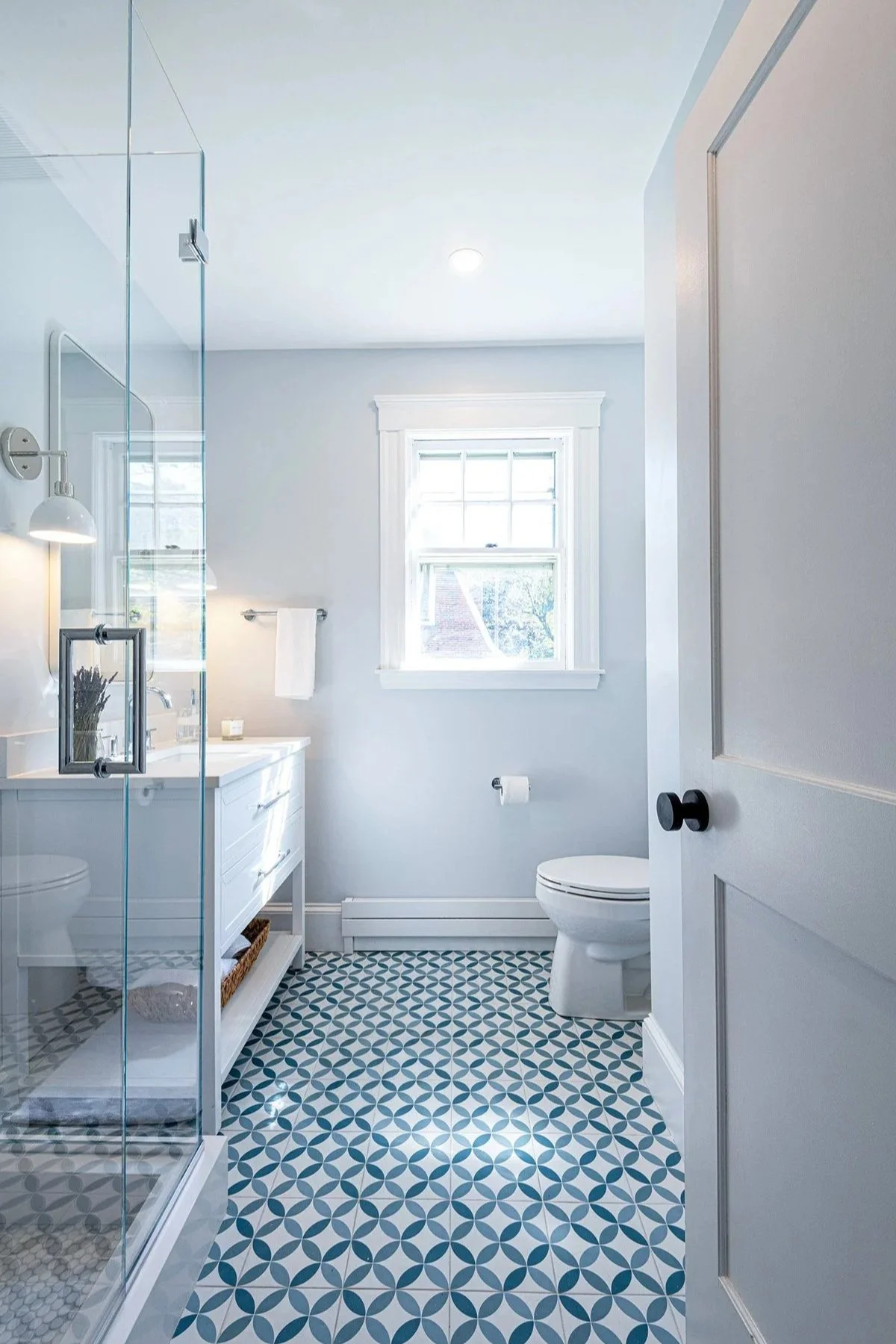 Open entry door into remodeled bathroom featuring blue and white circular patterned floor tile