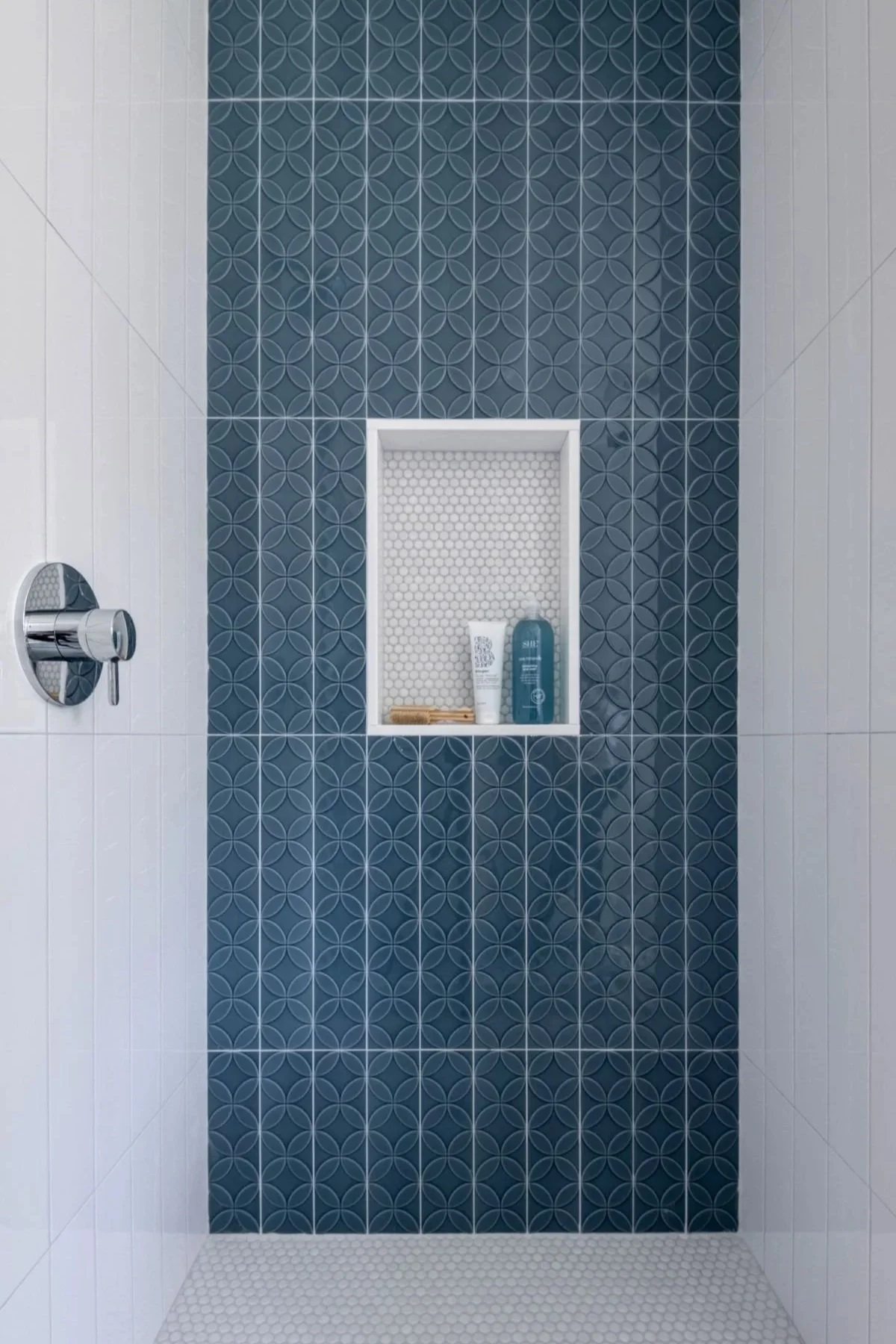 A modern shower accent feature wall in a Medford bathroom, showcasing circular geometric tile patterns and a functional recessed storage niche.