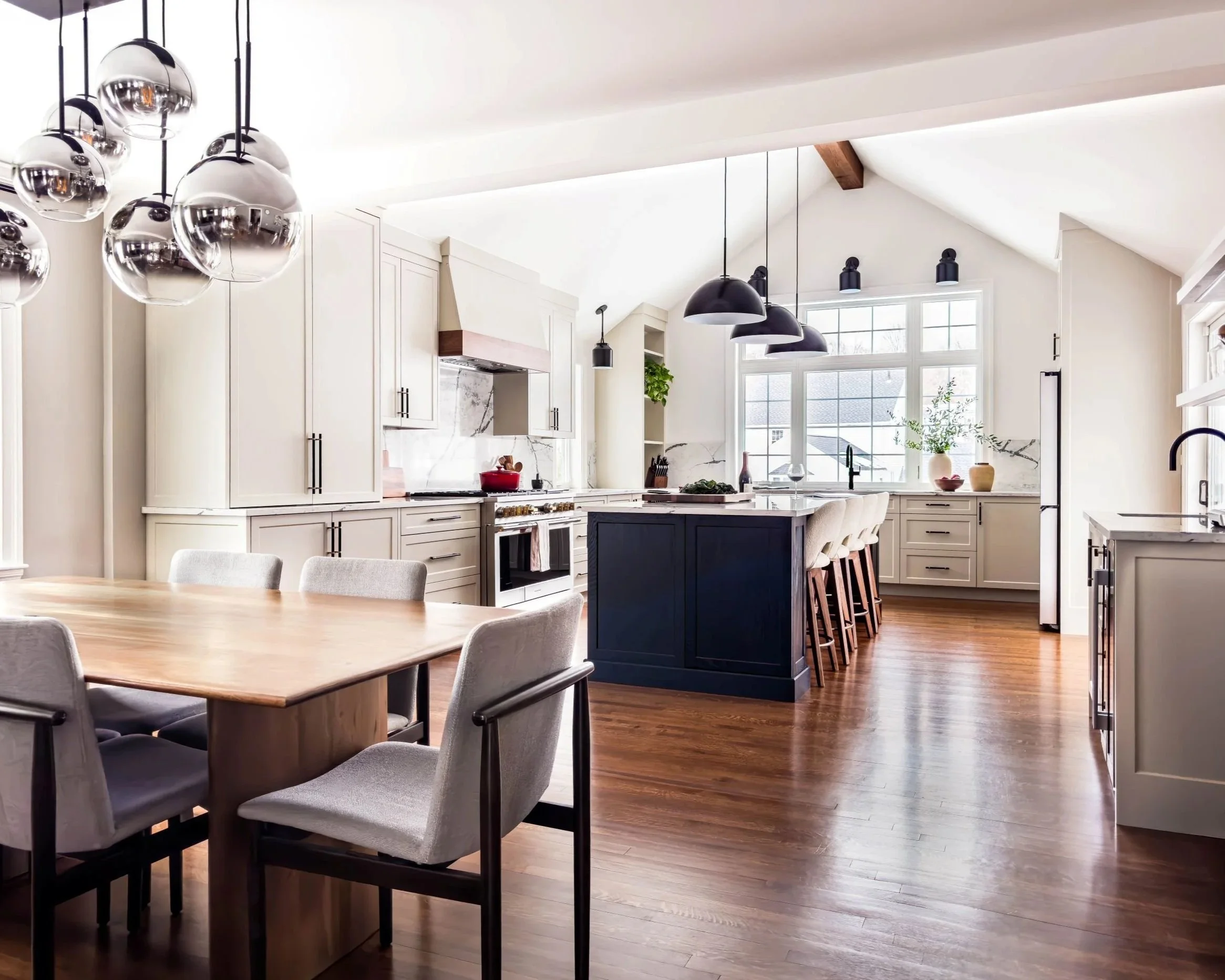 Renovated view of open dining room to kitchen with large black oak stained island and beige cabinetry.