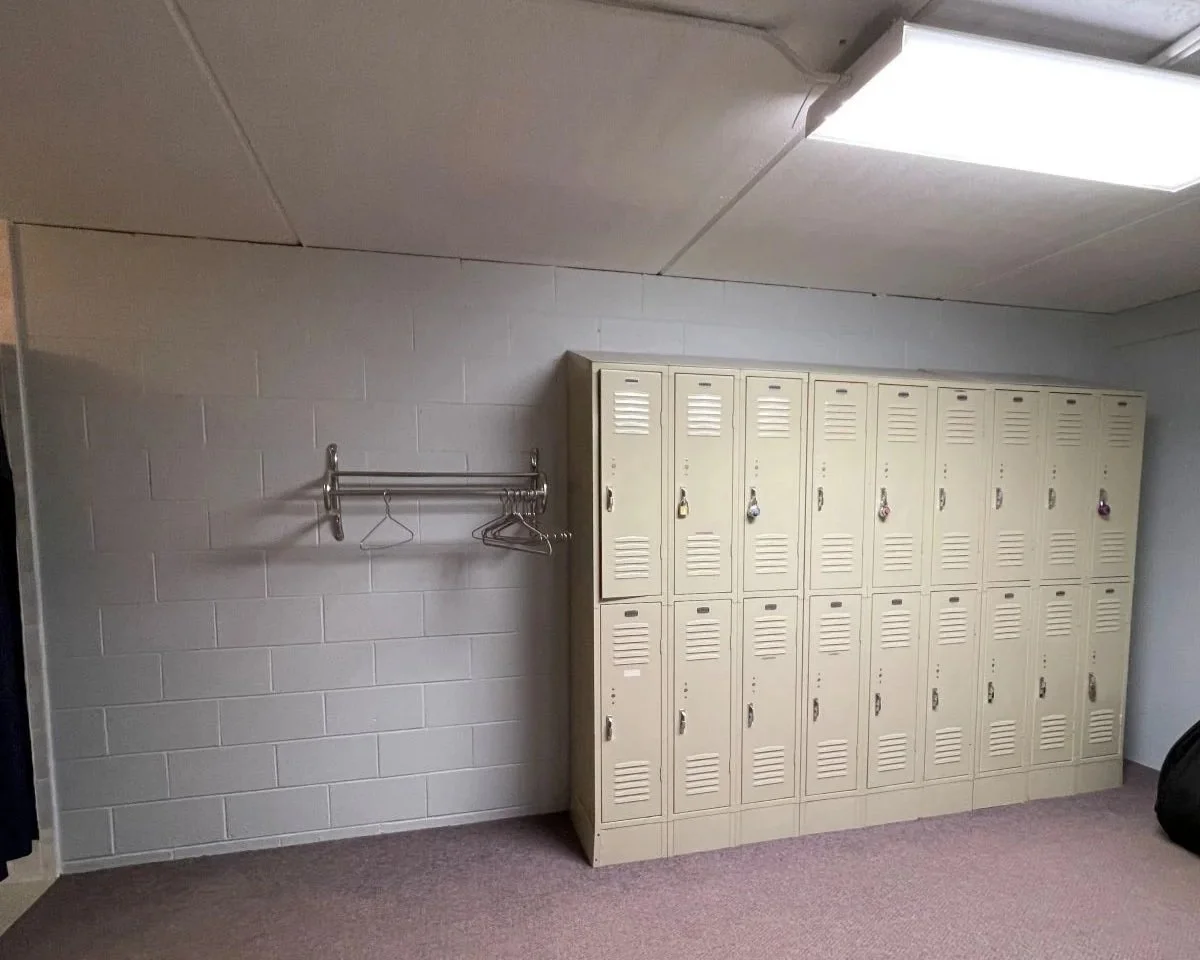 Original metal lockers in dated athletic facility locker room.