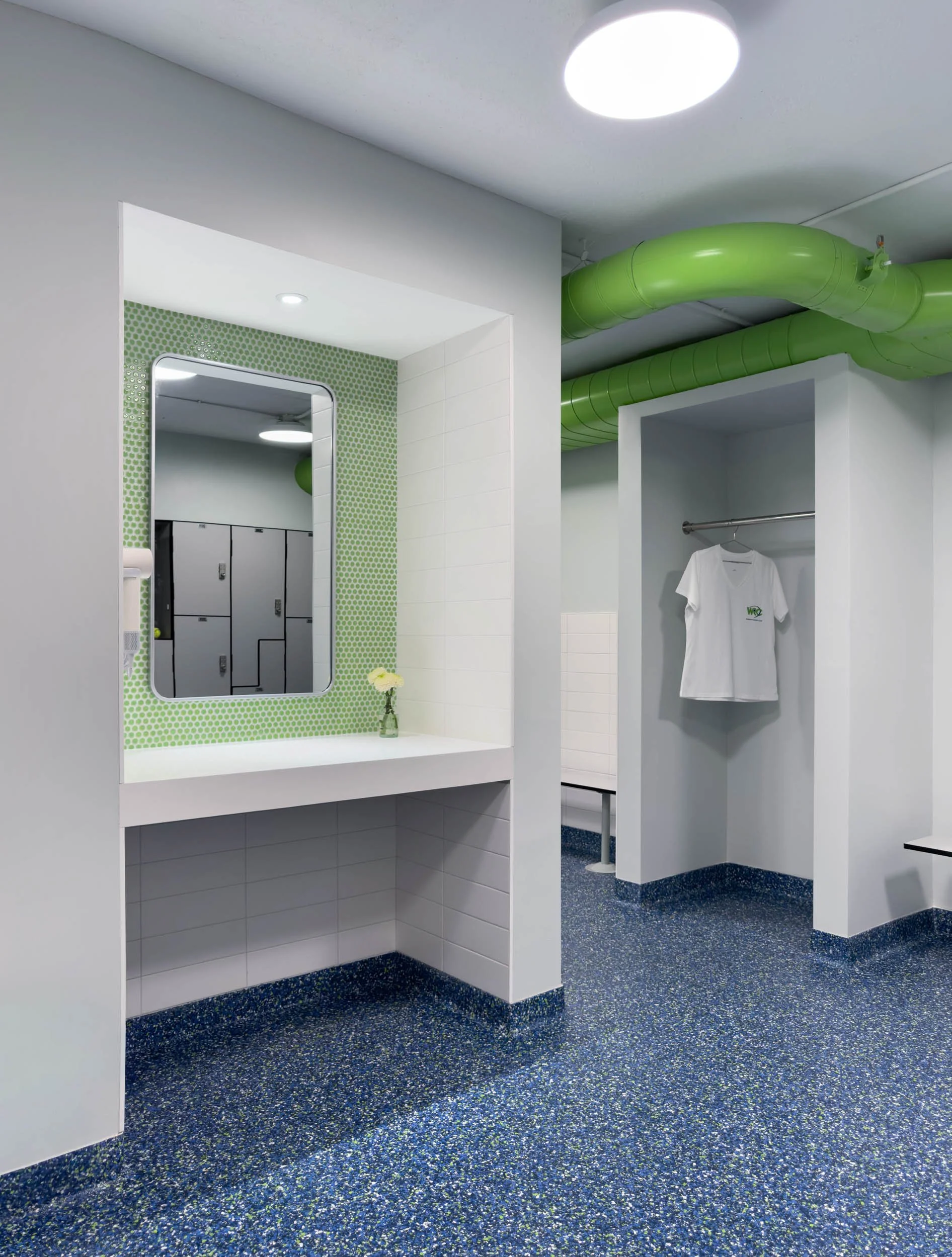 locker room vanity and hair drying station with white quartz countertop and apron with green penny tile backsplash