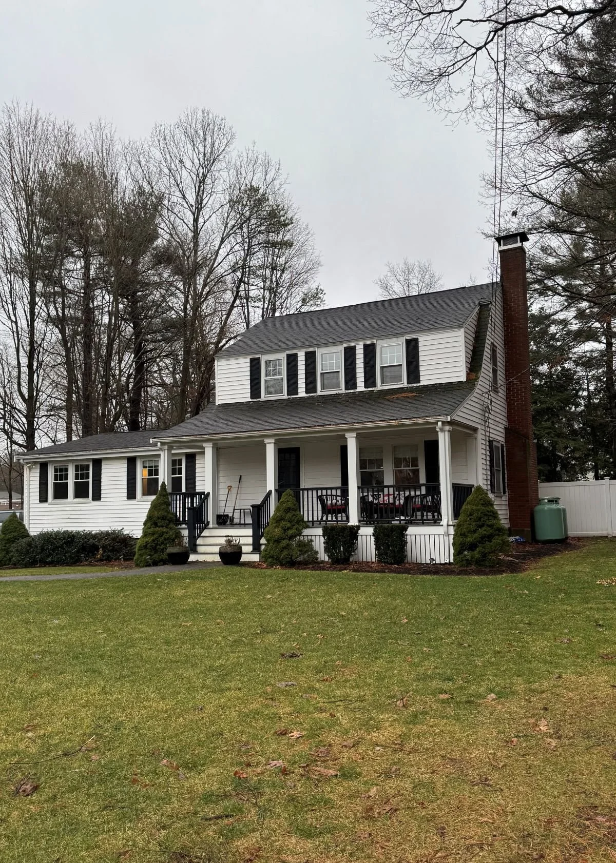 Existing side view of a Dutch Colonial home in Greater Boston prior to second story addition showing original one story addition profile before renovation by Tact and Grit Design Co.