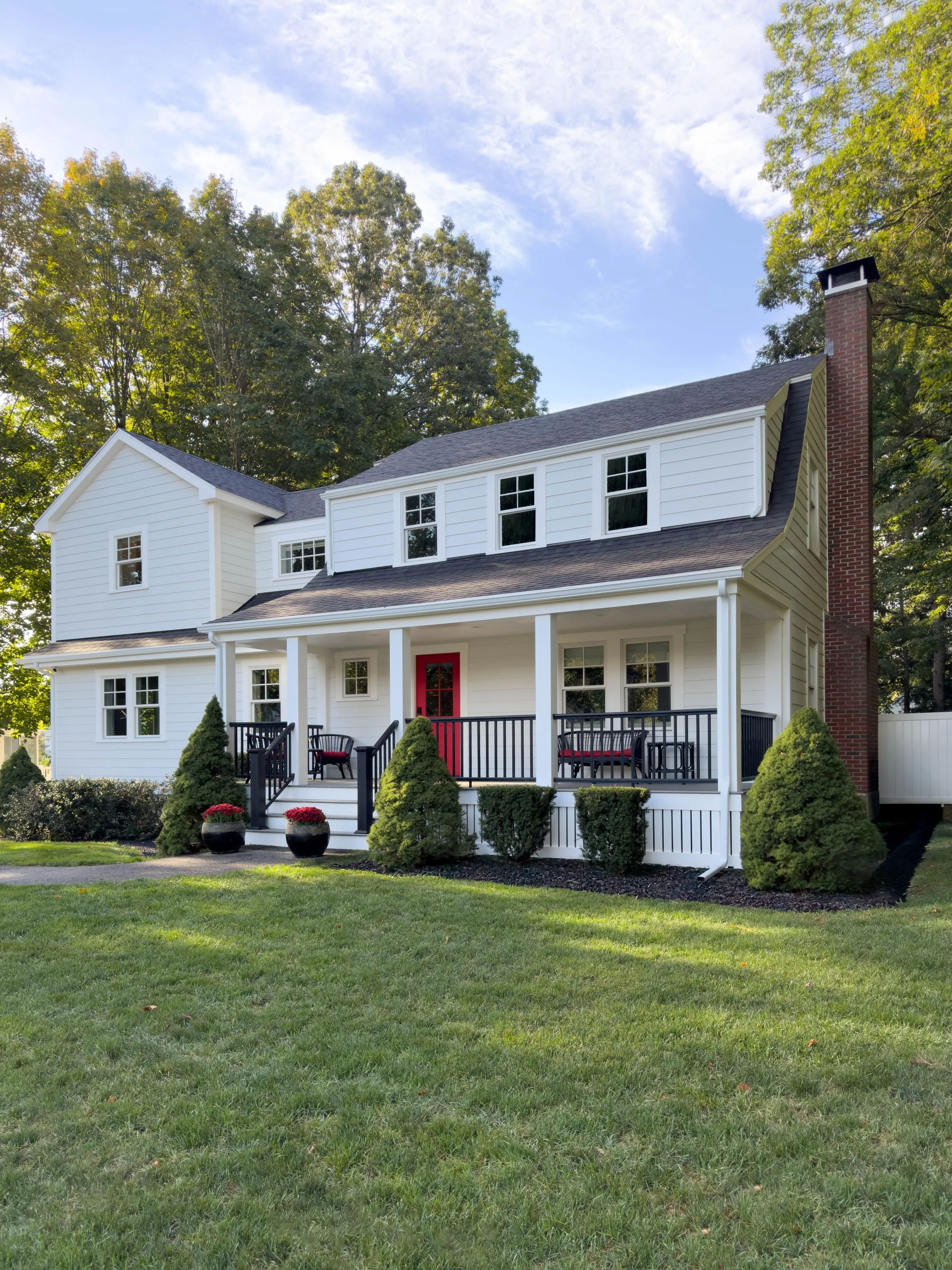 Completed front facade of a Dutch Colonial second story addition in Greater Boston showing new Hardie siding, Marvin windows, covered front porch and second story addition by Tact and Grit Design Co.