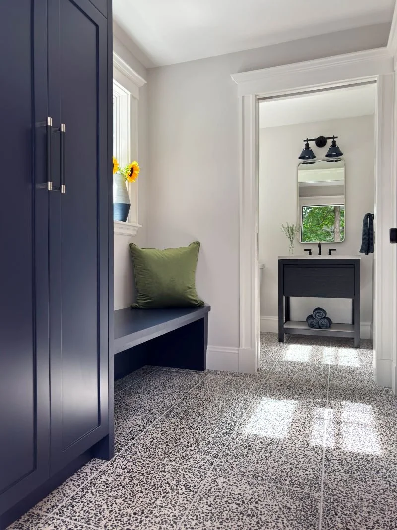 Bespoke interior design for a residential entryway featuring a functional mudroom reconfiguration with custom blue cabinetry and built-in bench seating.