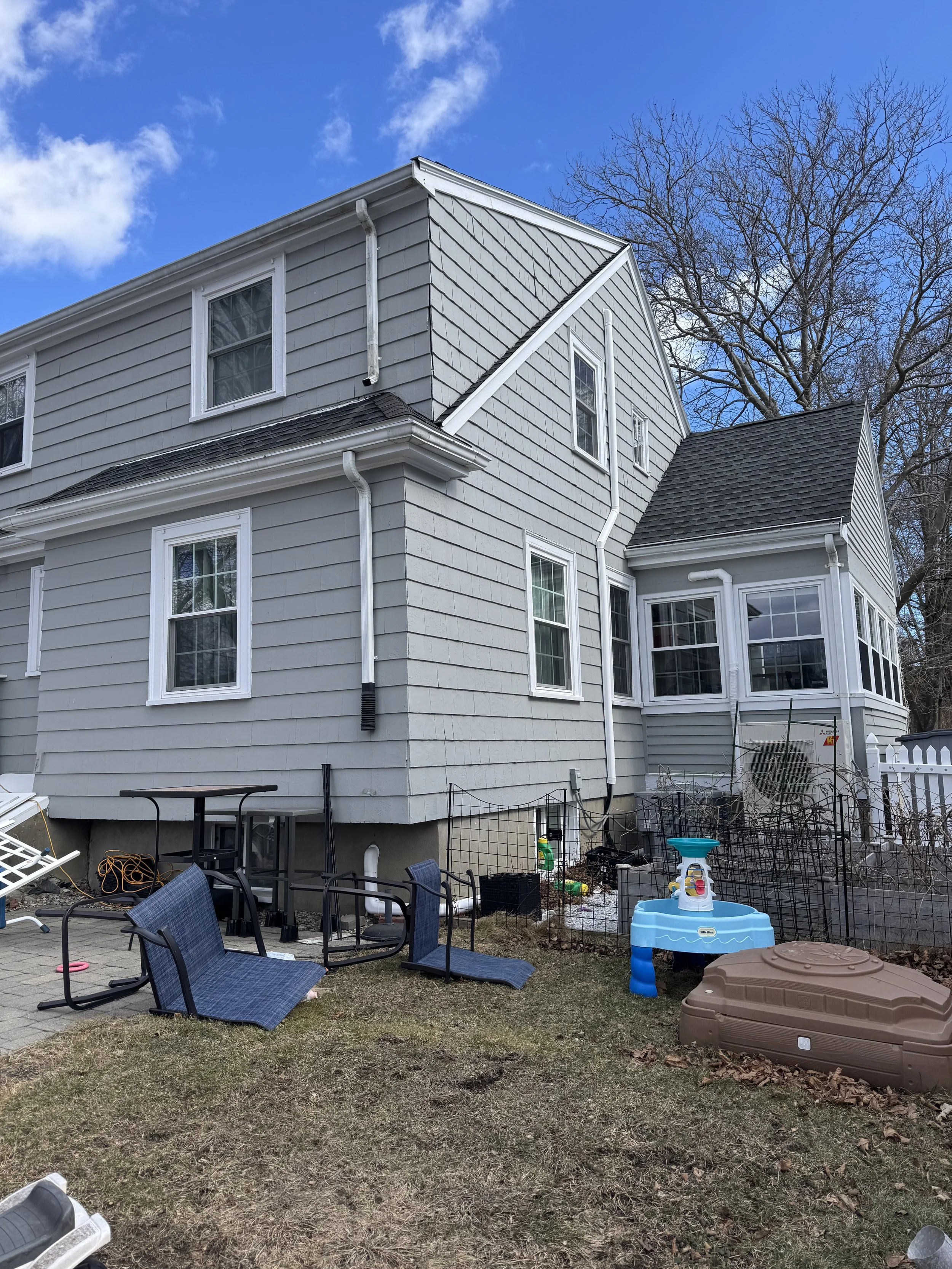 Side view of existing conditions of a colonial home in Melrose, MA prior to vaulted kitchen addition and basement stair walkout, designed by Tact and Grit Design Co.