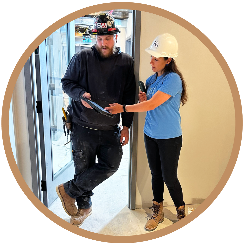 Architect Olivia Dube performing on-site electrical coordination with a subcontractor in Boston, reviewing digital plans to resolve field conditions during the construction phase.