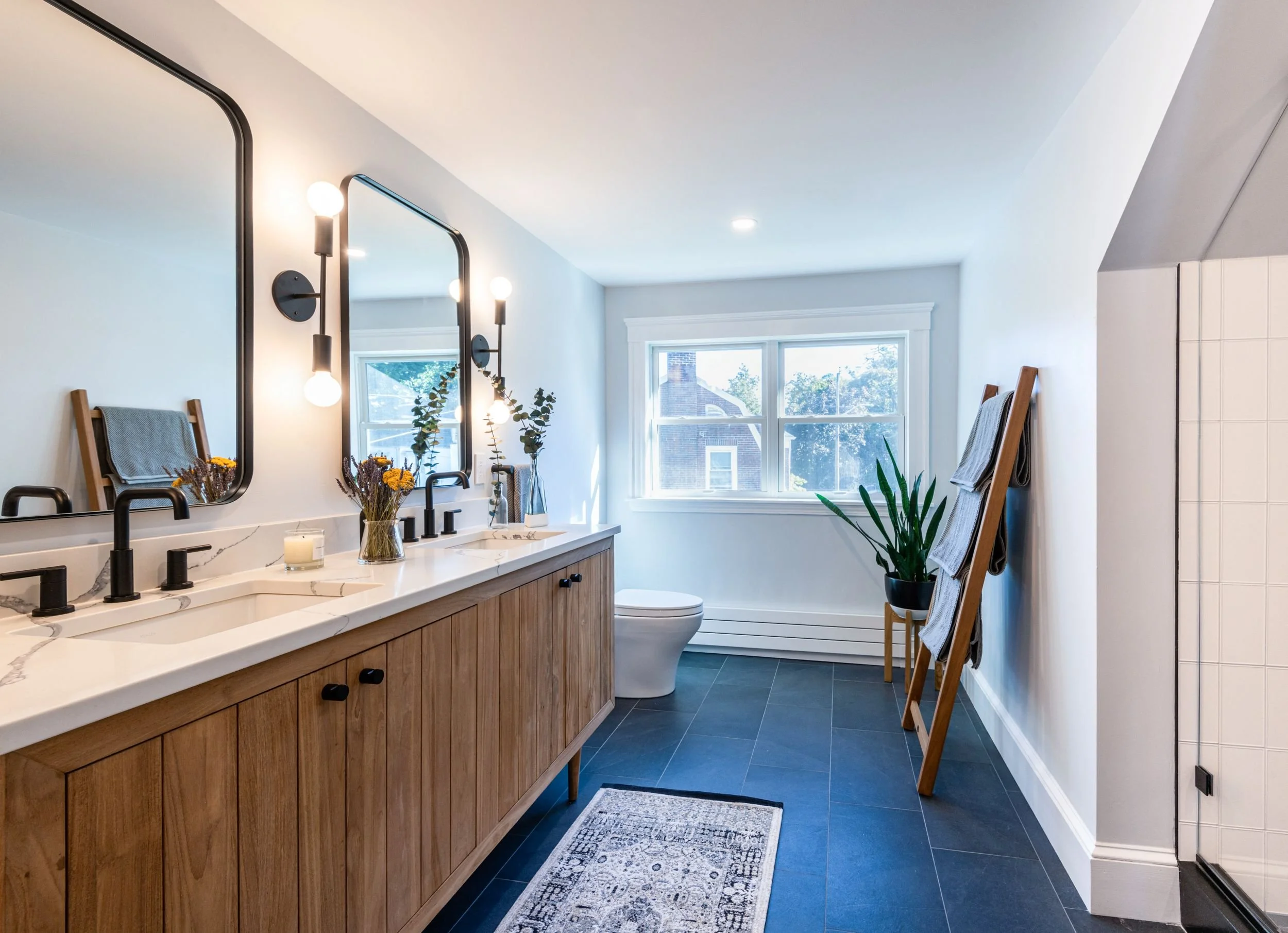 modern primary bathroom featuring teak vanity with double sinks and towel ladder and double hung windows in Medford, MA