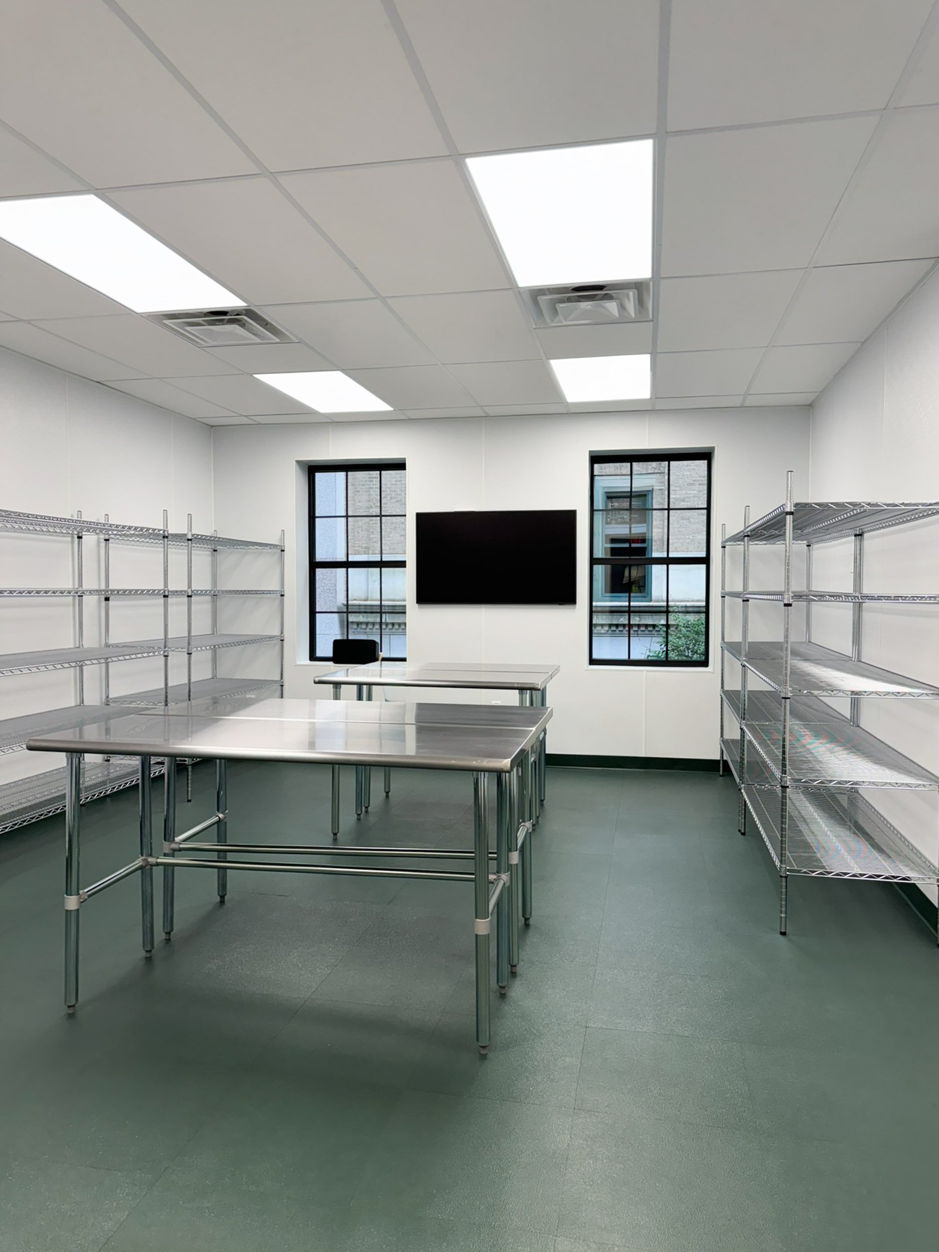 A packaging and processing room with stainless steel tables, wall shelving and a drop ceiling for easy to clean surfaces