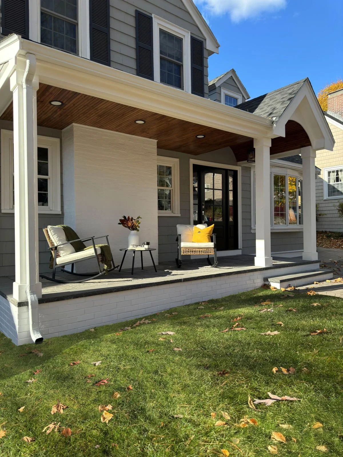 Exterior profile of the Melrose porch addition, showcasing the clean lines of the white columns and the substantial concrete and granite paver floor. This perspective highlights the successful integration of the new structure with the home's original