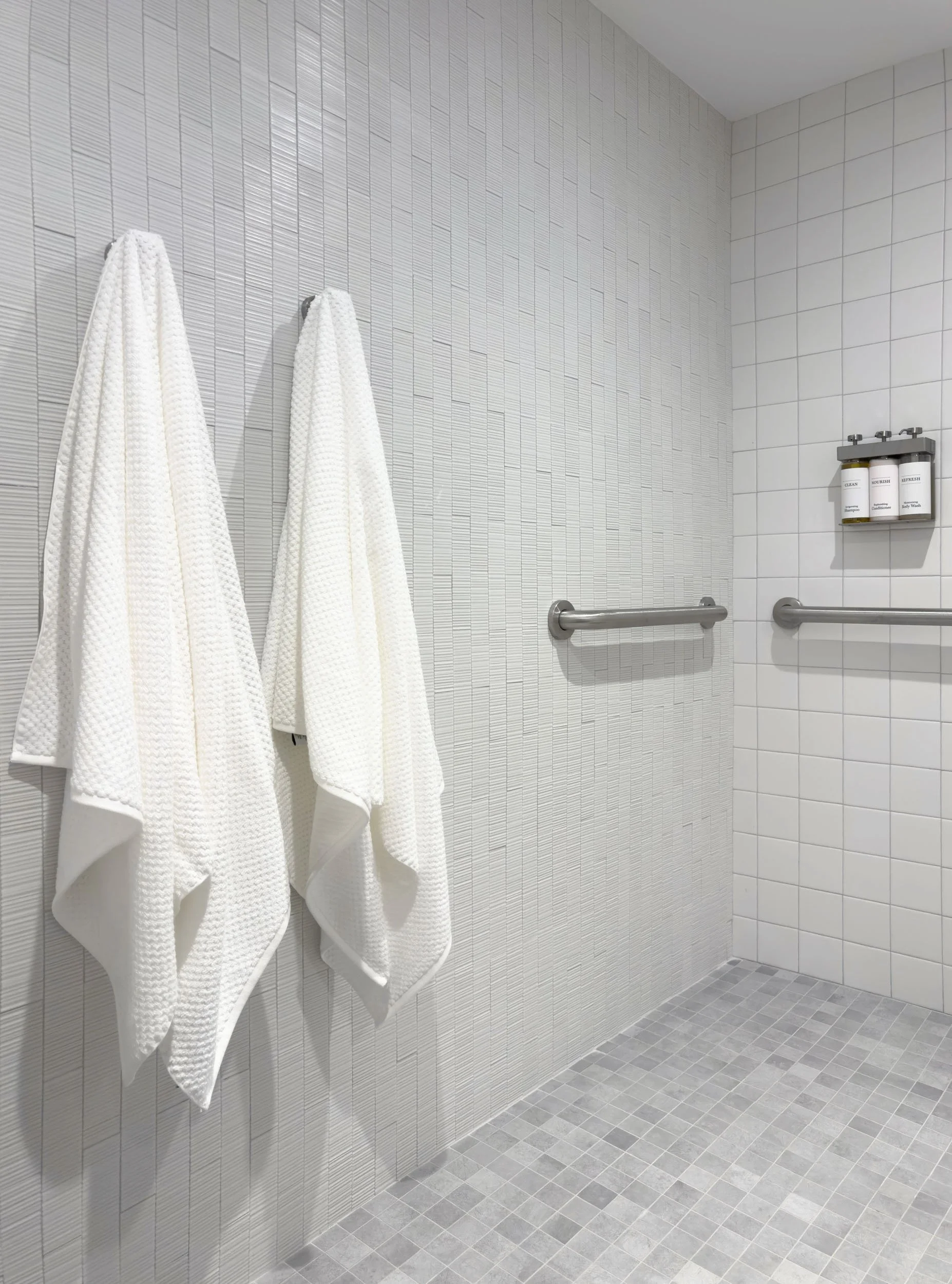 interior of accessible shower featuring accent tile wall and square floor tile