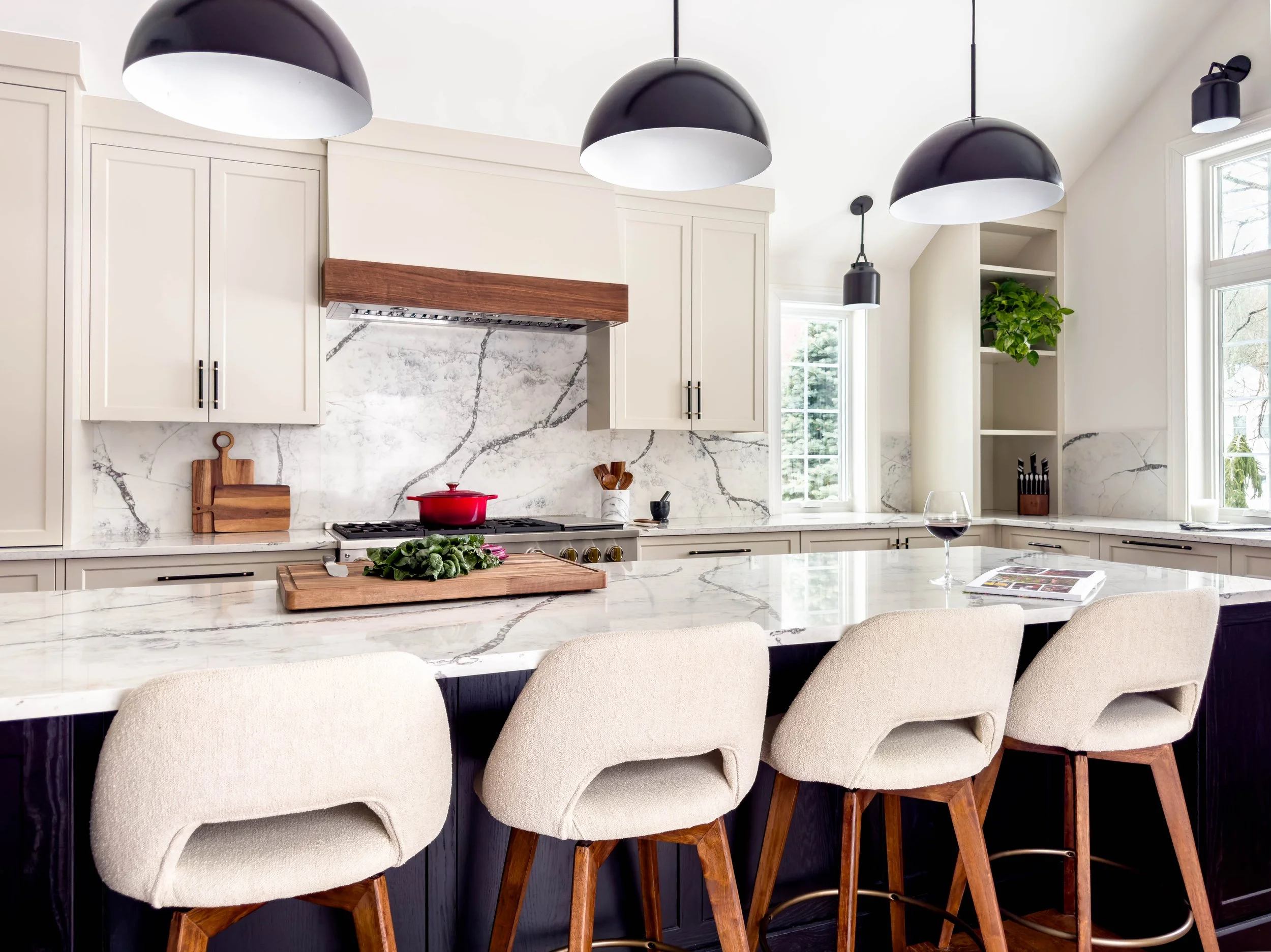 Oversized kitchen island in black stained oak with marble-style quartz counters, providing comfortable seating for four in a vaulted addition.