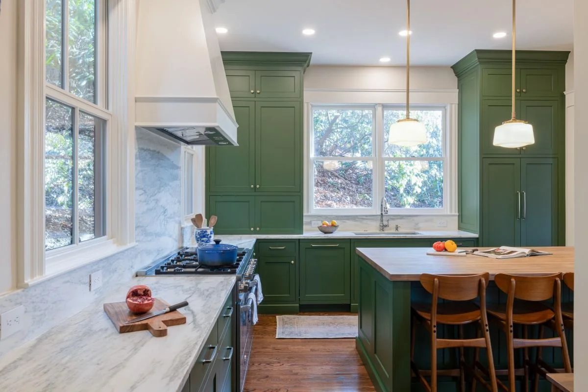 "Completed kitchen renovation in a Newton Victorian home, featuring custom sage green cabinetry, a marble backsplash and countertops, and a butcher block style island with  pendant lighting.
