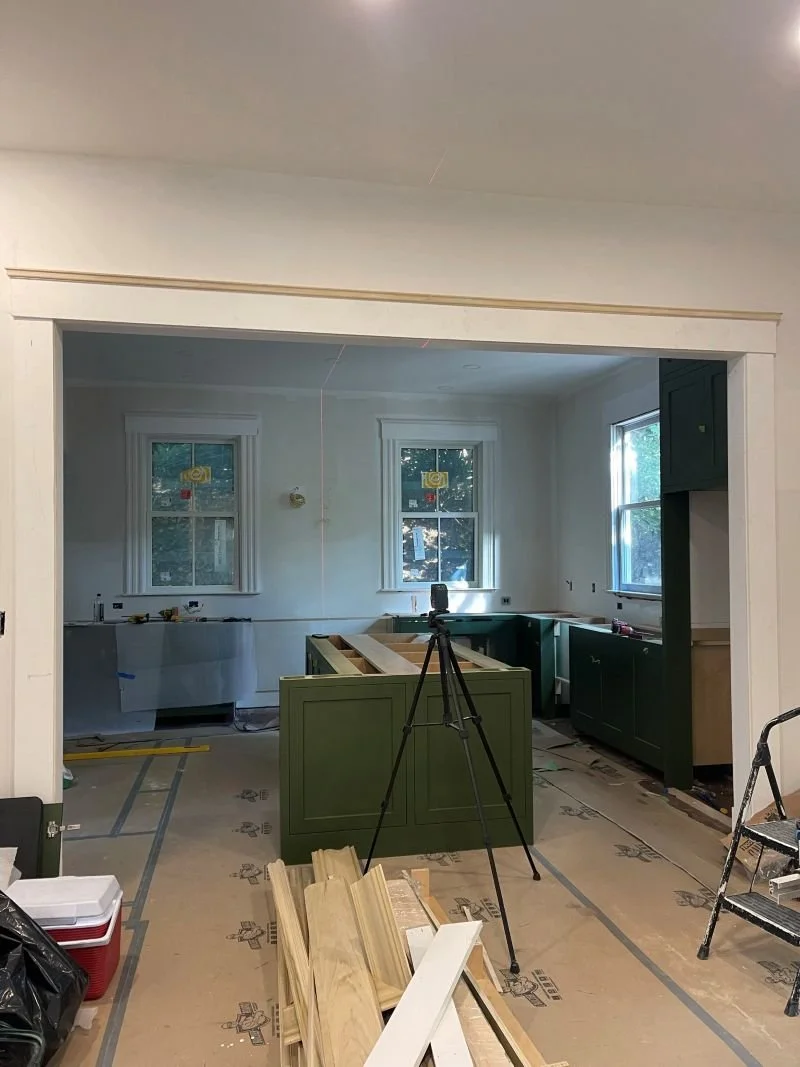 Precision installation of custom sage green cabinetry using laser alignment, highlighting the attention to detail in the final finish phase.