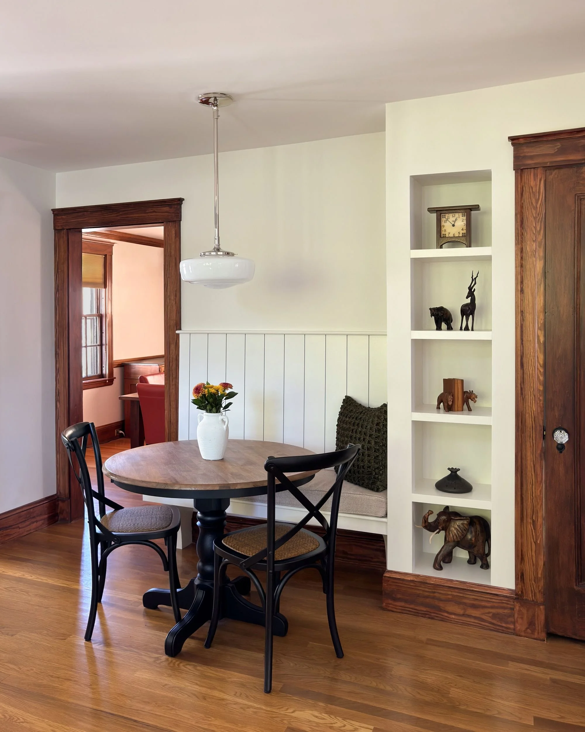 Breakfast nook with round pedestal table, built-in bench seating, and original Dutch Colonial millwork and built-in shelving, Medford MA kitchen addition