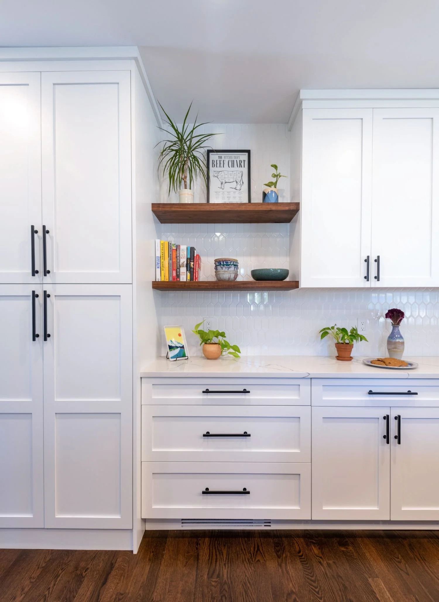 Accent walnut floating shelves integrated in wall of custom white cabinetry with black hardware