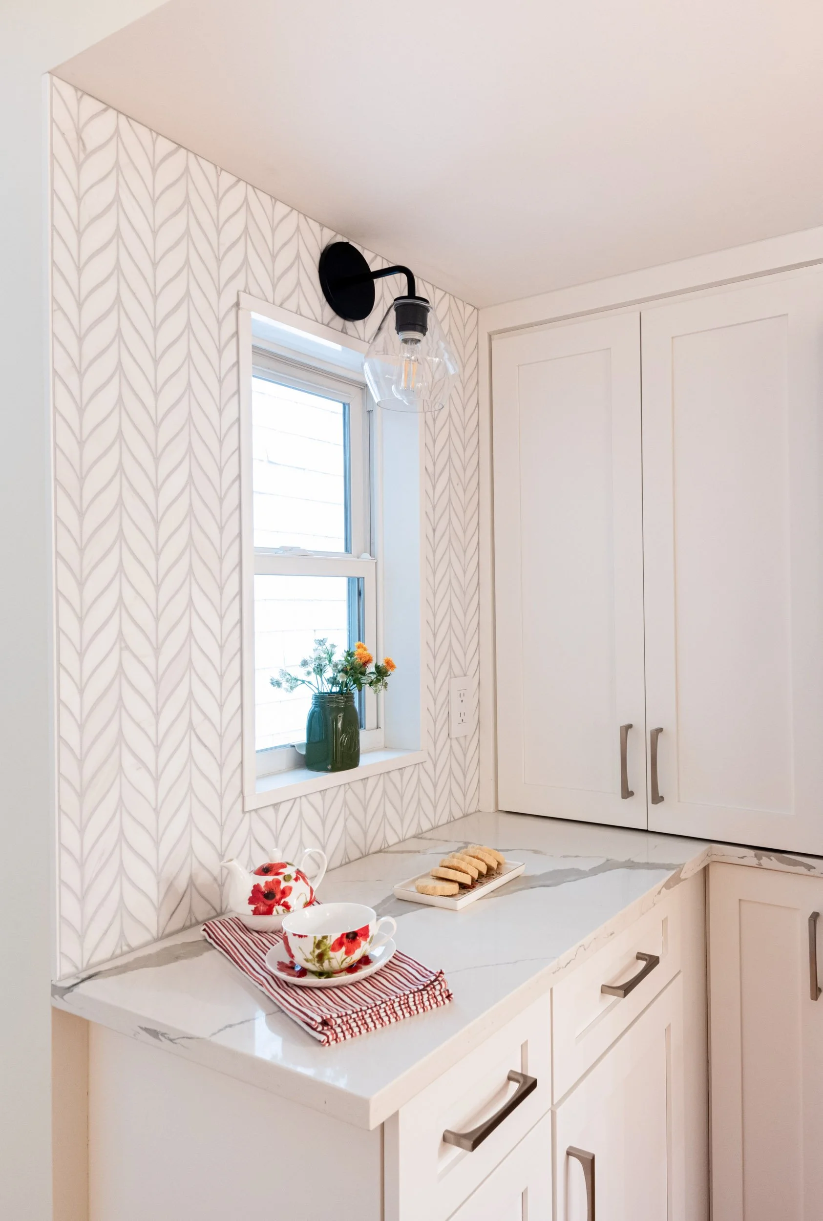 A coffee nook with marble leaf mosaic tile and a wall sconce.