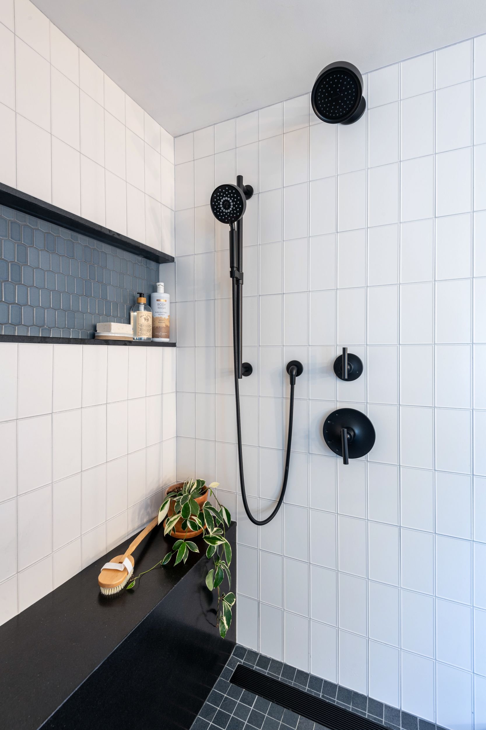 Detail view of walk-in-shower with black accents in primary bathroom in Medford, MA