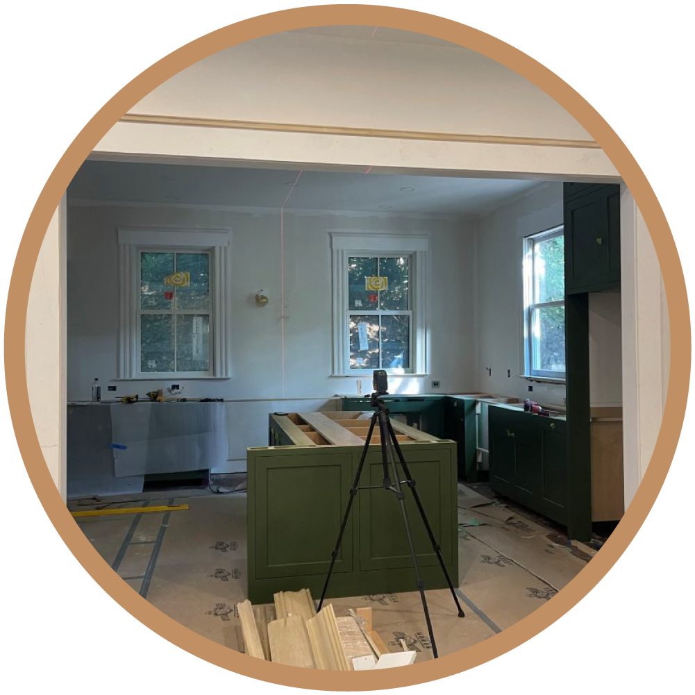 Precision installation of custom sage green cabinetry using laser alignment, highlighting the attention to detail in the final finish phase.