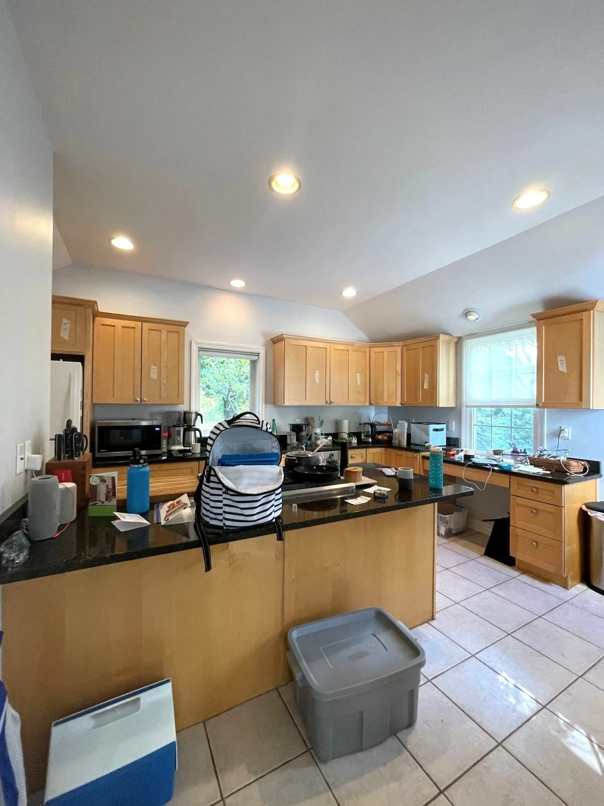 The existing kitchen with honey oak cabinetry and black countertops in Bedford colonial prior to renovation.