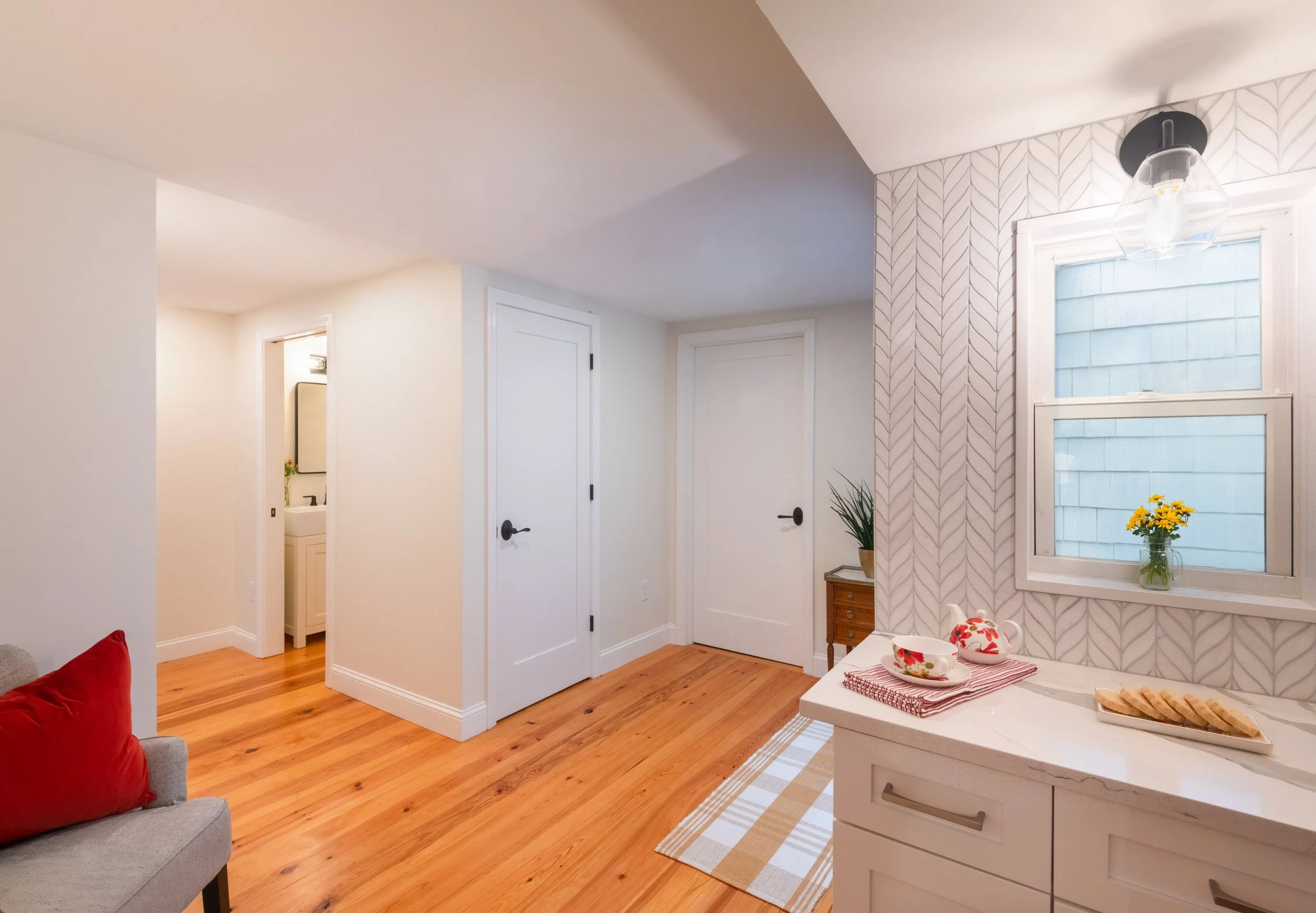 Central circulation nook featuring coffee station, reading chair, powder room, door to pantry closet and door to primary suite.