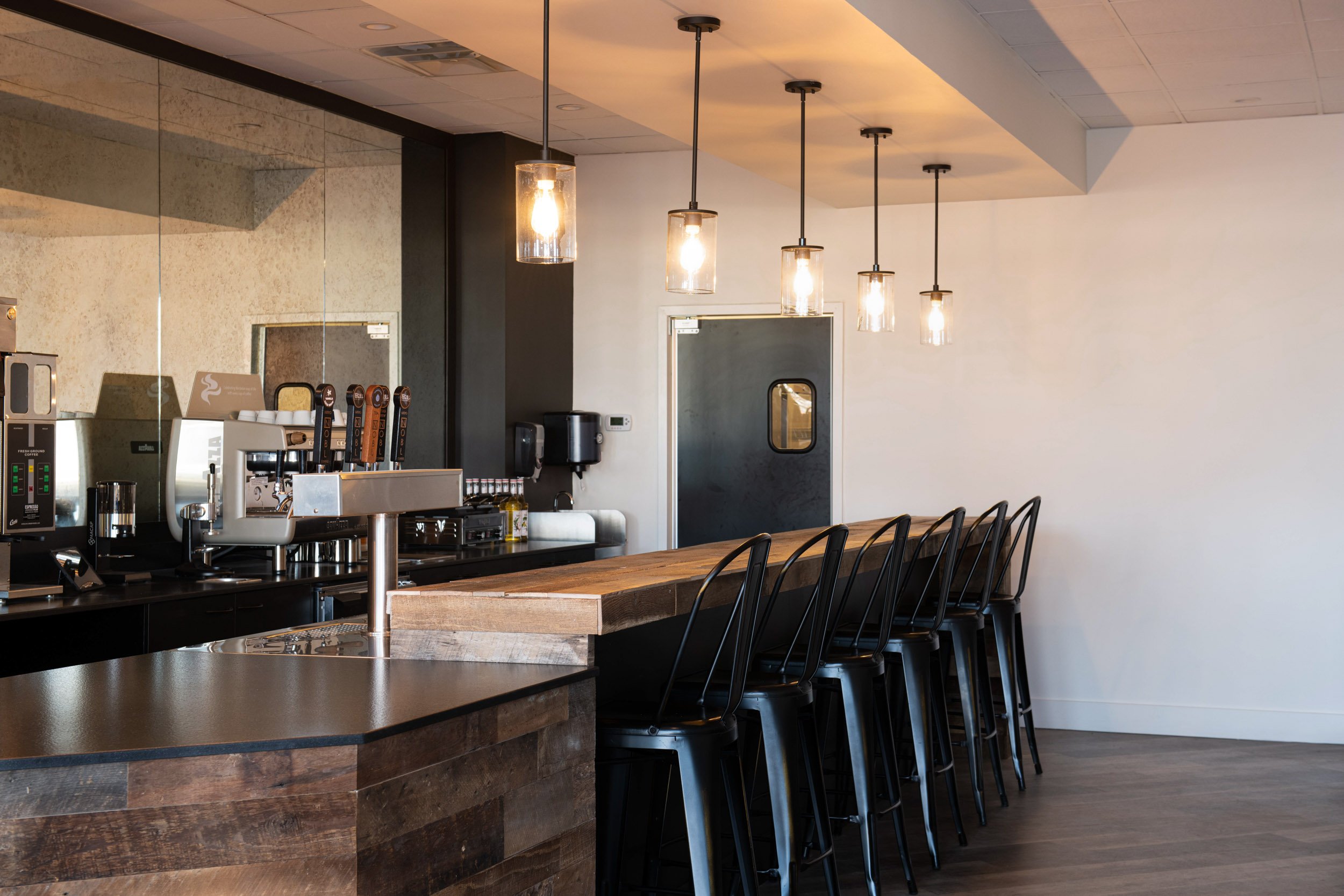 black granite and rustic wood coffee bar featuring bronze stools and equipment