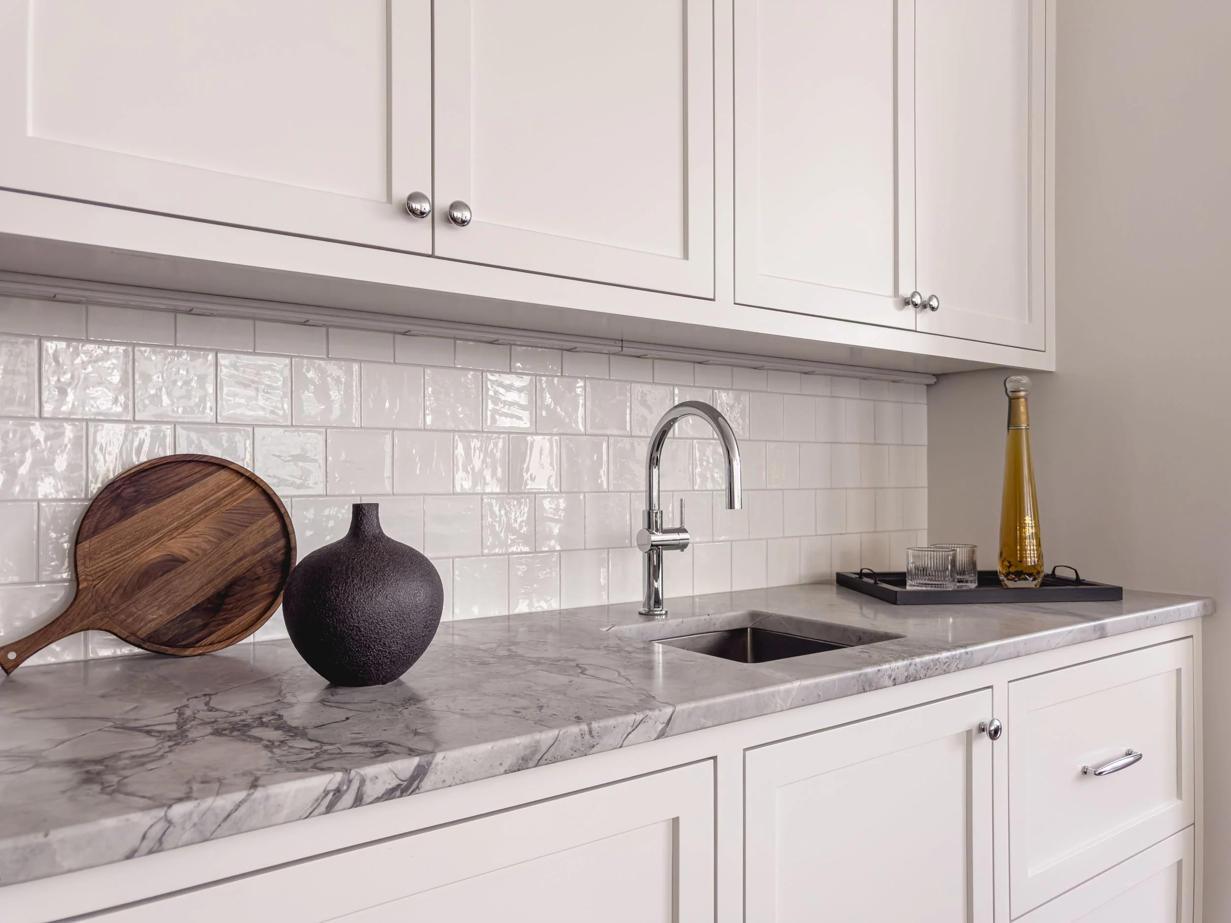 Wet bar with custom inset white cabinetry, natural stone quartzite countertop, undermount sink, gooseneck faucet, and square subway tile backsplash in Hamilton MA home by Tact & Grit Design Co.