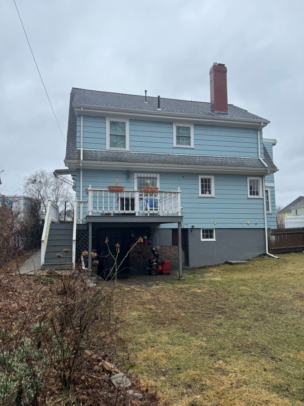 Existing rear exterior of Dutch Colonial home in Medford MA before kitchen addition, showing original foundation and grade