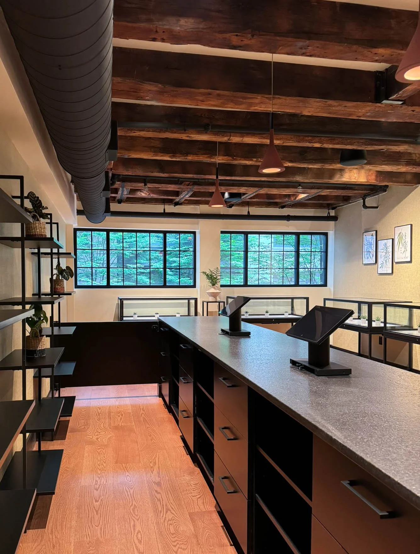Bright modern Jamaican inspired retail interior with a custom service counter, black steel shelving, and integrated track lighting that highlights 200-year-old exposed wood beams.