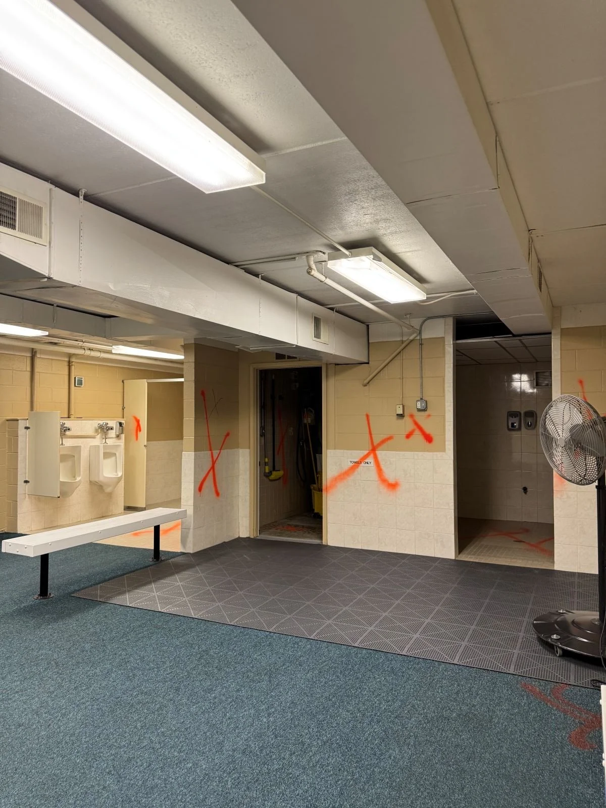 Existing overview of shower area with urinals beyond prior to a locker room renovation at Woburn Racquet Club