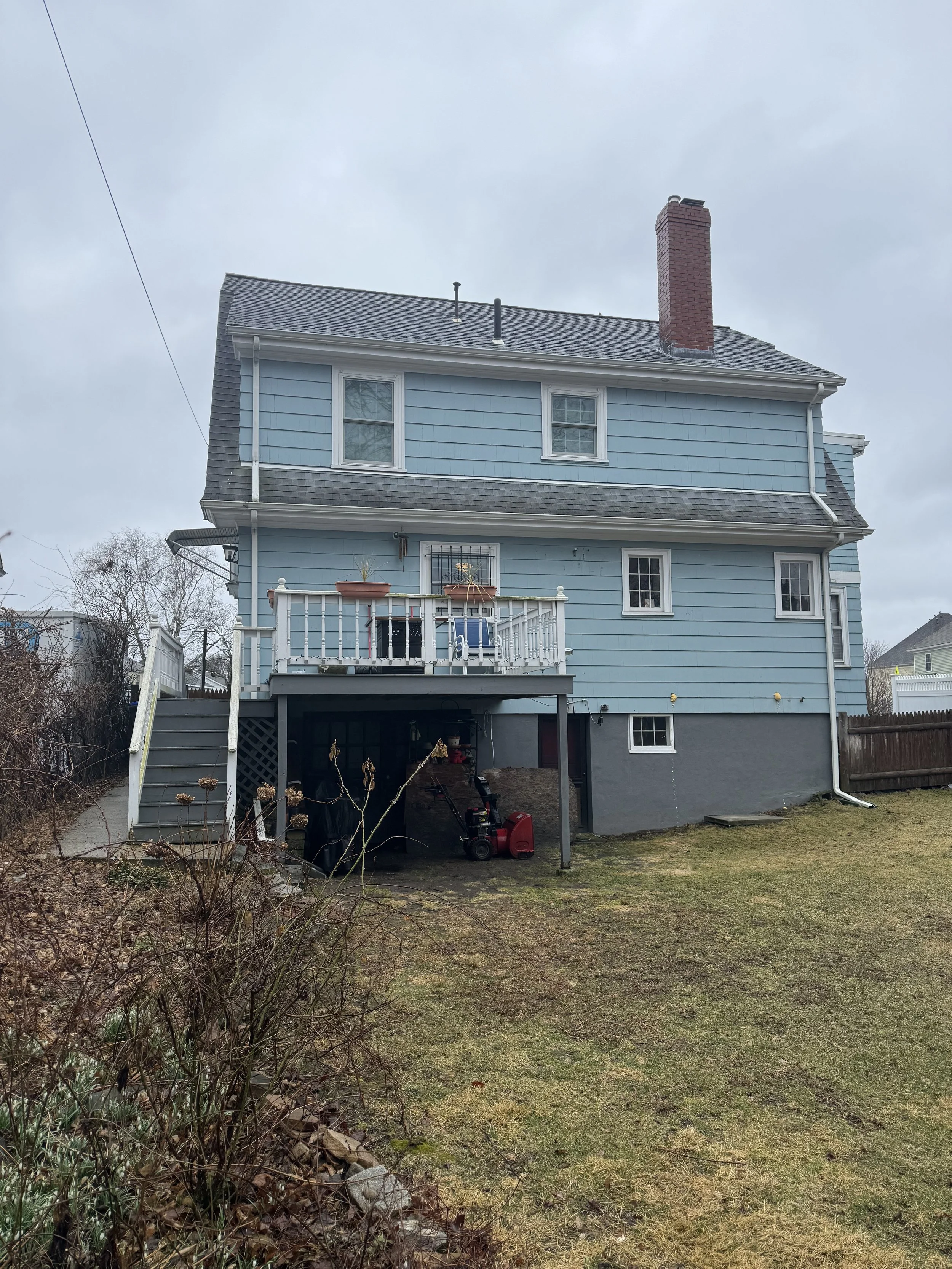 Rear exterior of a Dutch Colonial home in Medford, MA, showing the original gambrel roofline and underutilized rear entry prior to the kitchen addition.