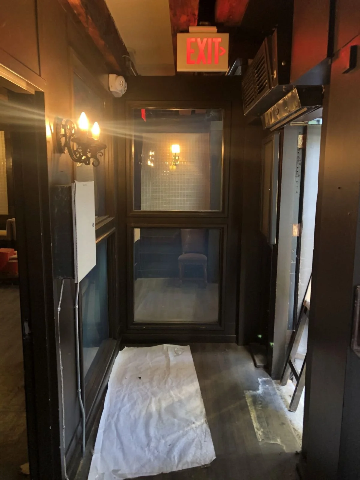 An entry vestibule with wood paneling and an illuminated exit sign