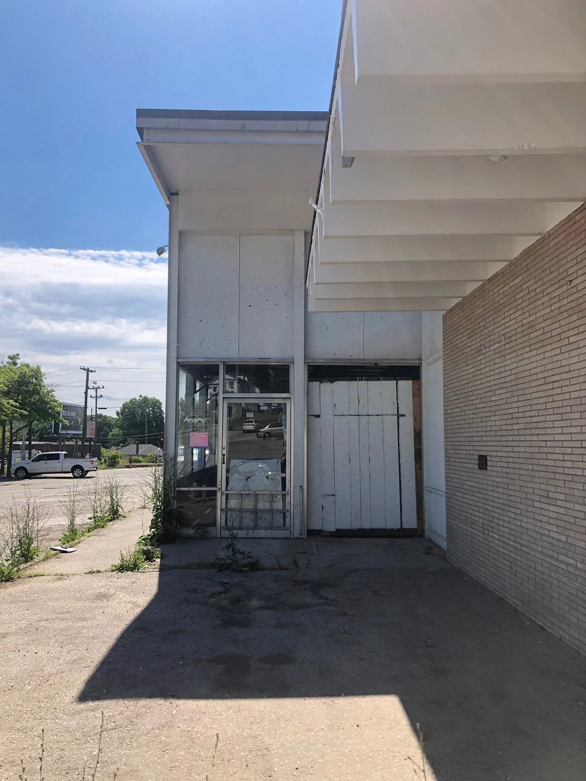 existing entry with exposed concrete beams and concrete sidewalk of a vacant retail warehouse