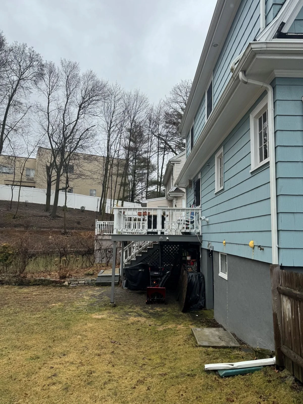 Existing rear exterior of Dutch Colonial home in Medford MA before kitchen addition, showing original deck and foundation