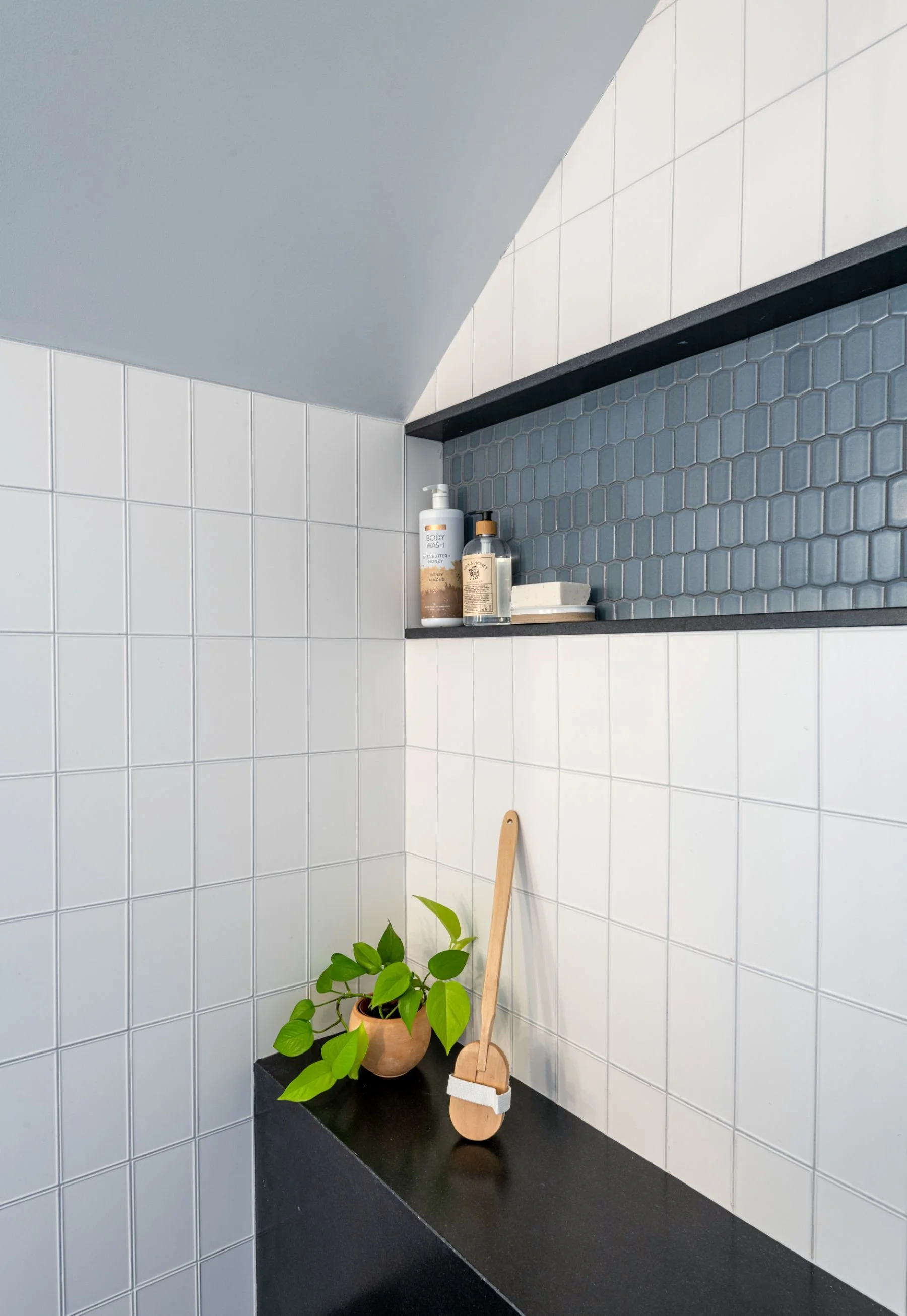 horizontal niche detail with black granite stone waterfall bench in primary bathroom in Medford, MA